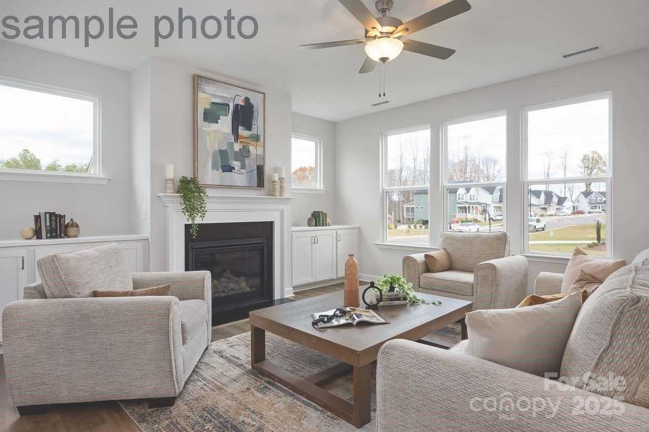 Cozy living room with gas fireplace, beige sofas, large windows overlooking yard in Davidson Homes The Chestnut F, Belmont, NC