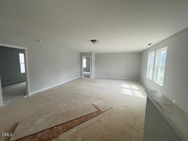 Spacious unfinished upstairs room with gray walls, large windows, doorways, and plywood subfloor in 4-bedroom Adalynn B home, Lillington, NC
