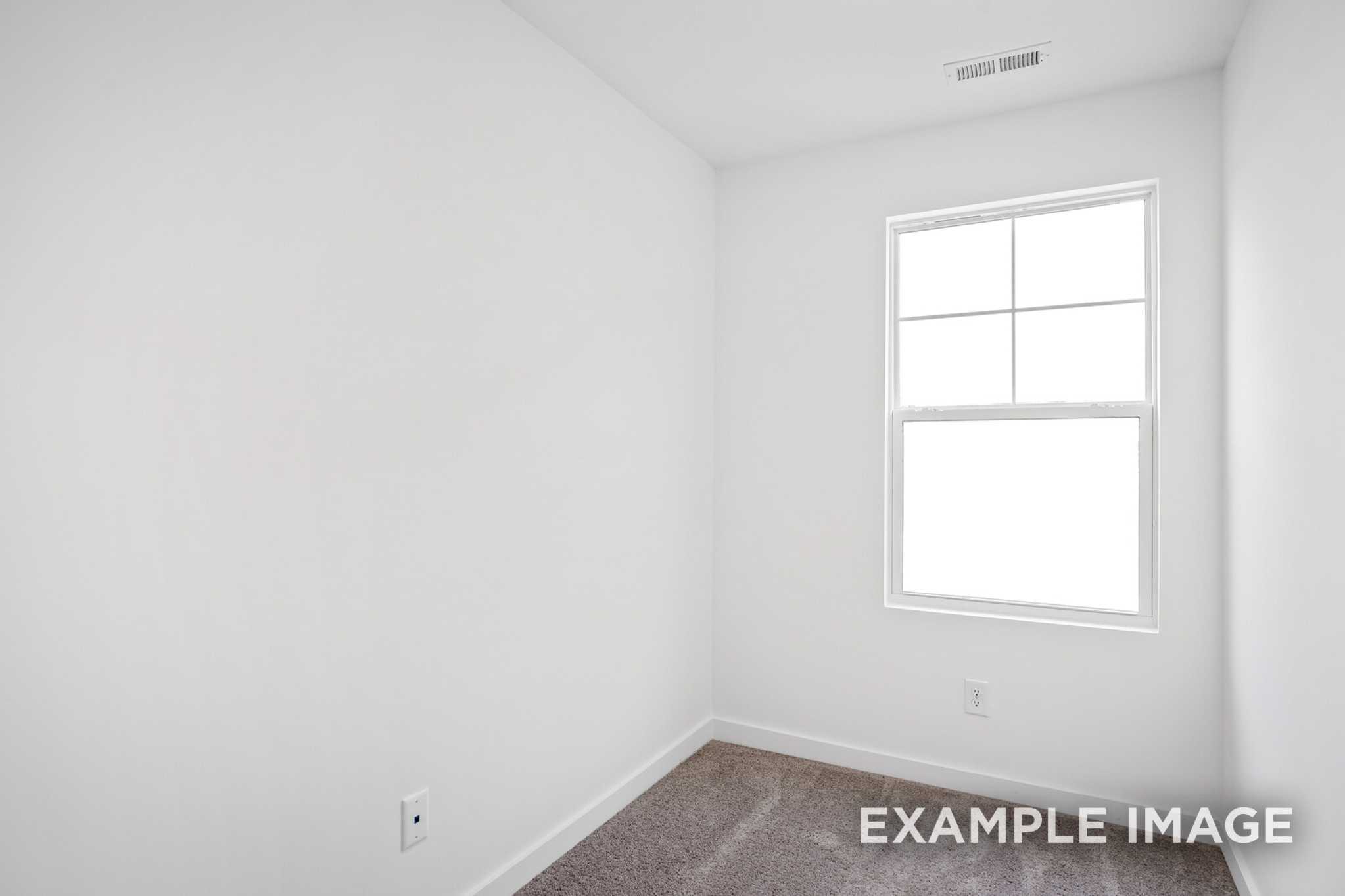 Spacious secondary bedroom in The Grayson C with white walls, large window, carpeted floor
