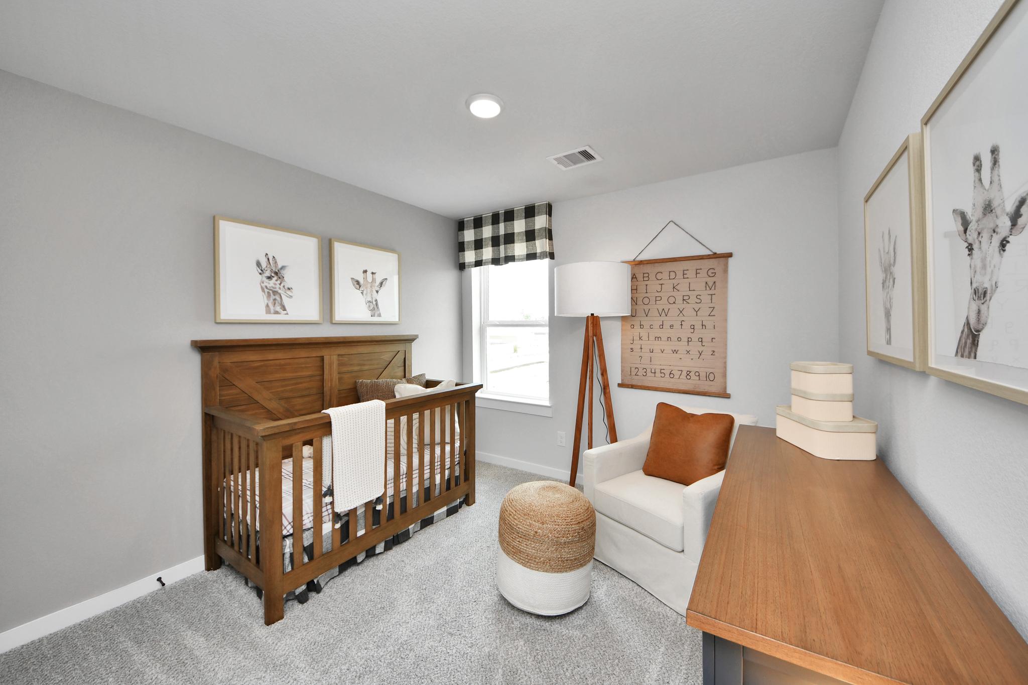 Modern nursery in Robins Landing, Houston, featuring a wooden crib, cozy armchair, and giraffe-themed decor by Davidson Homes.