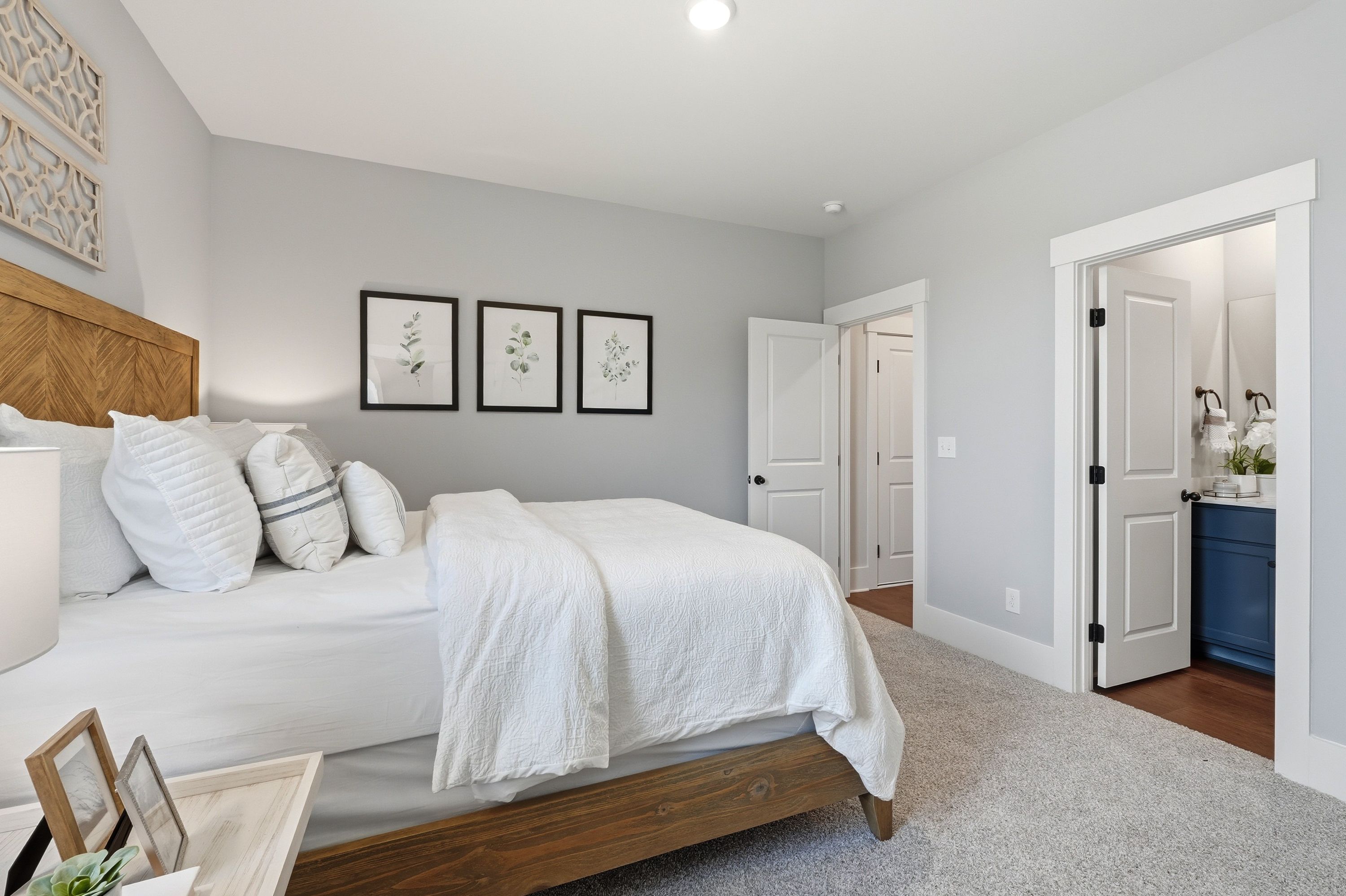 Spacious master bedroom at Noble Ridge in Cullman Alabama with gray walls wooden bed white bedding and en-suite bath