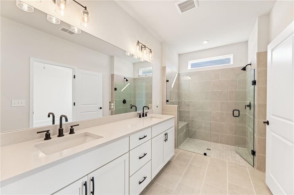 Modern master bathroom with double vanity, quartz counters, frameless glass shower in Davidson Homes The Glenwood A, Loganville, GA