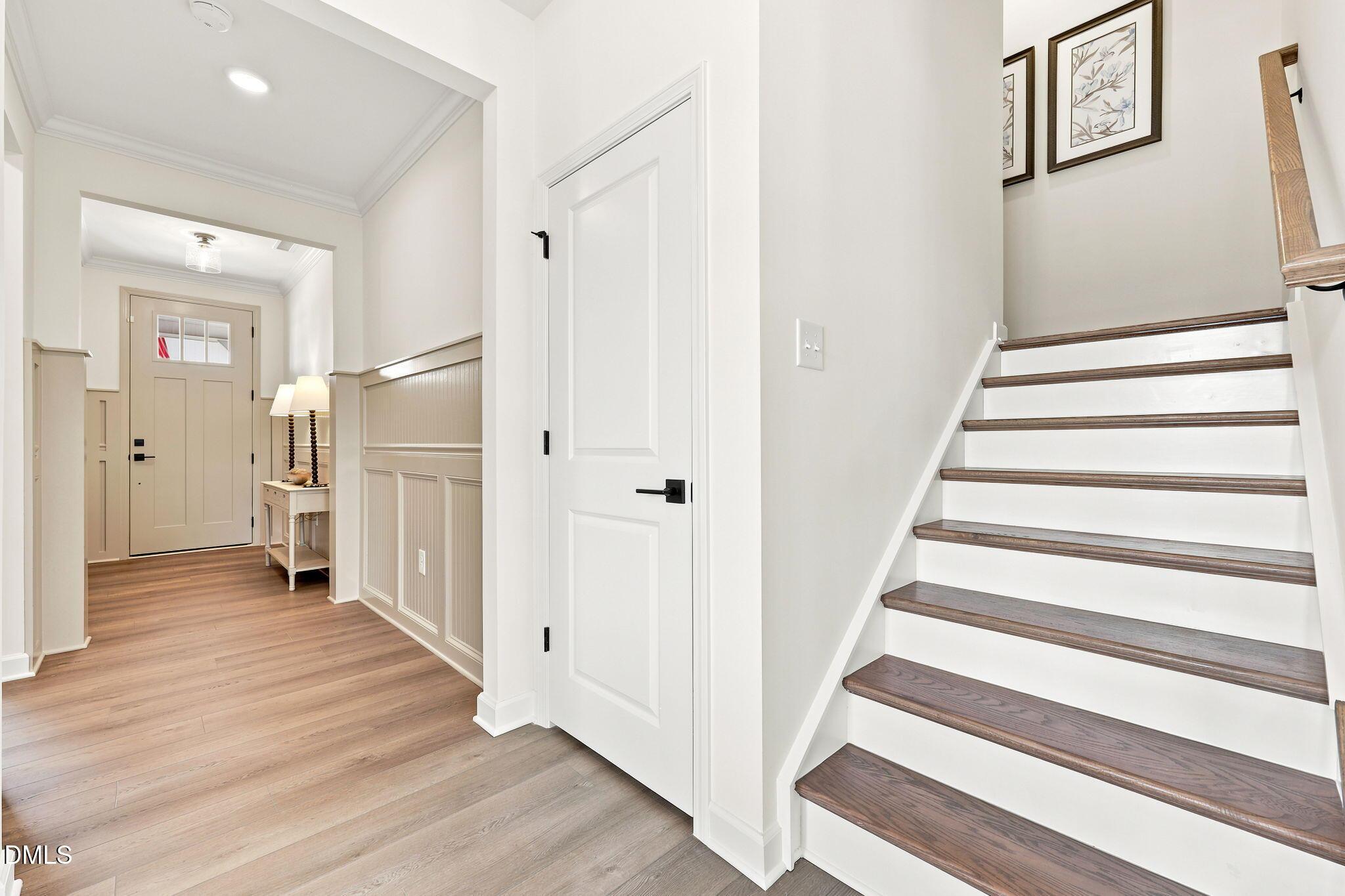 Bright entryway with hardwood floors and wooden staircase in The Beech B floor plan at Addison West, Holly Springs, NC.