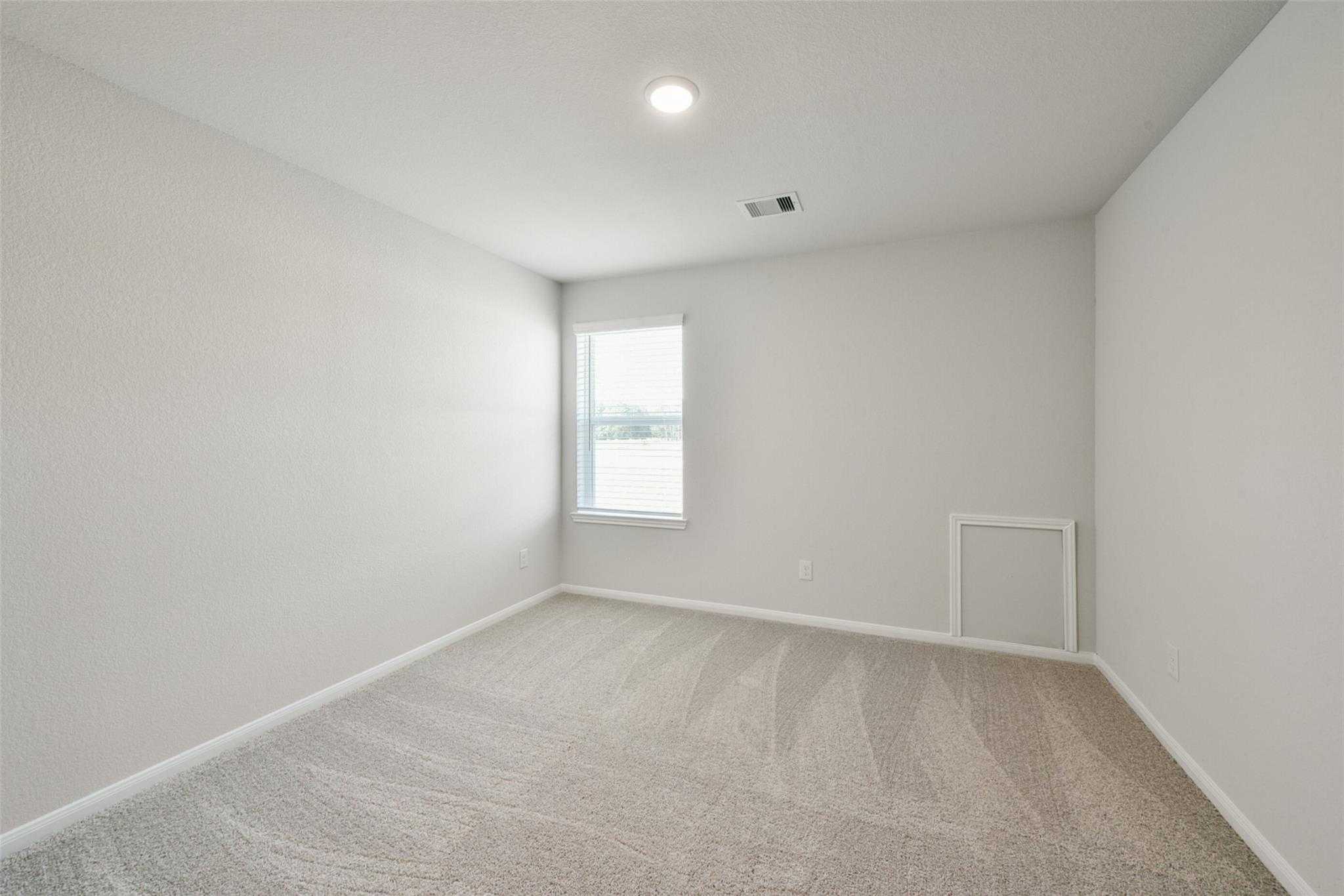 Bright secondary bedroom with light gray walls, beige carpet, large window in Davidson Homes The Sabine E, Dayton, Texas