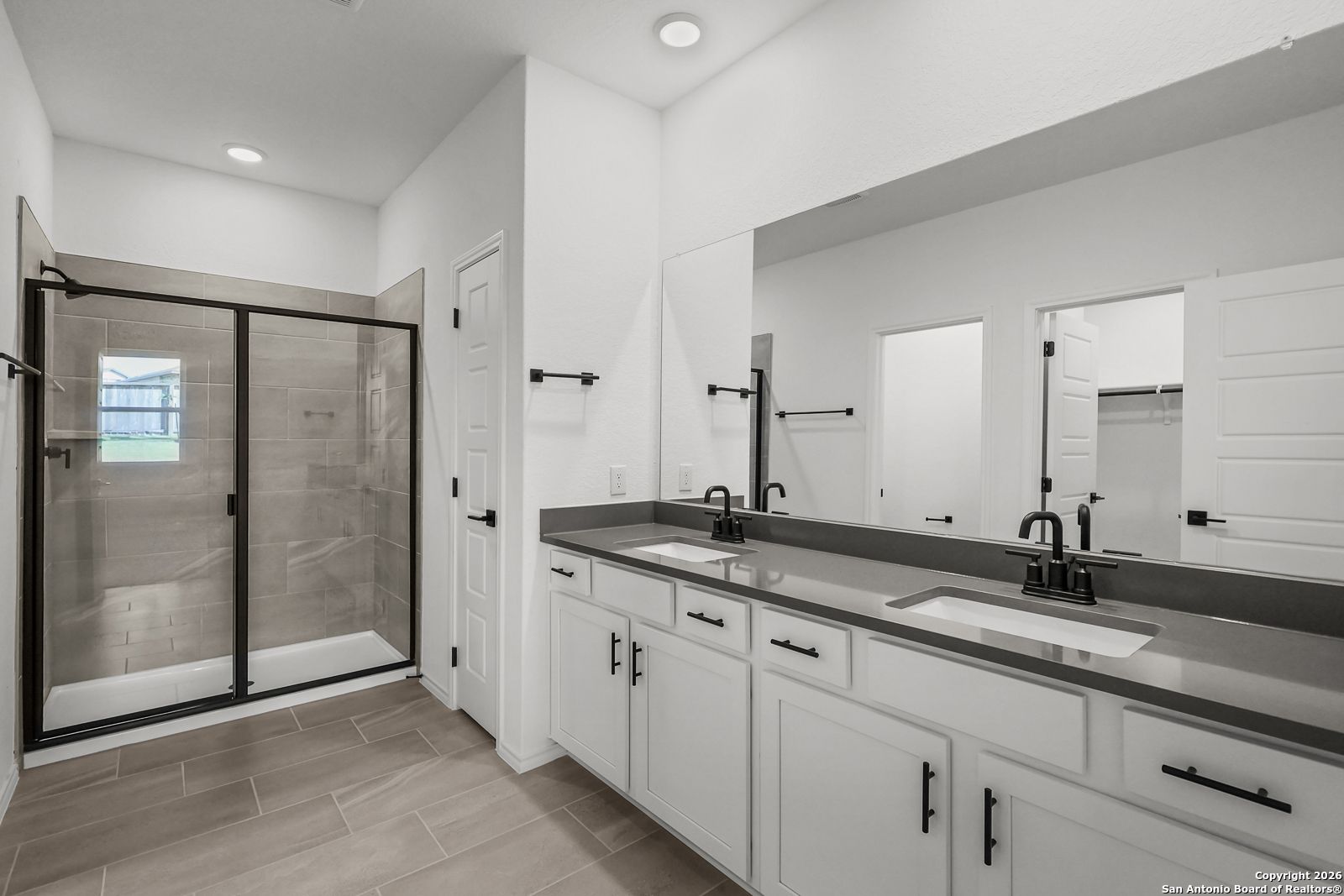Modern master bathroom featuring glass shower, double vanity with white cabinets in Davidson Homes The Douglas E, San Antonio, Texas