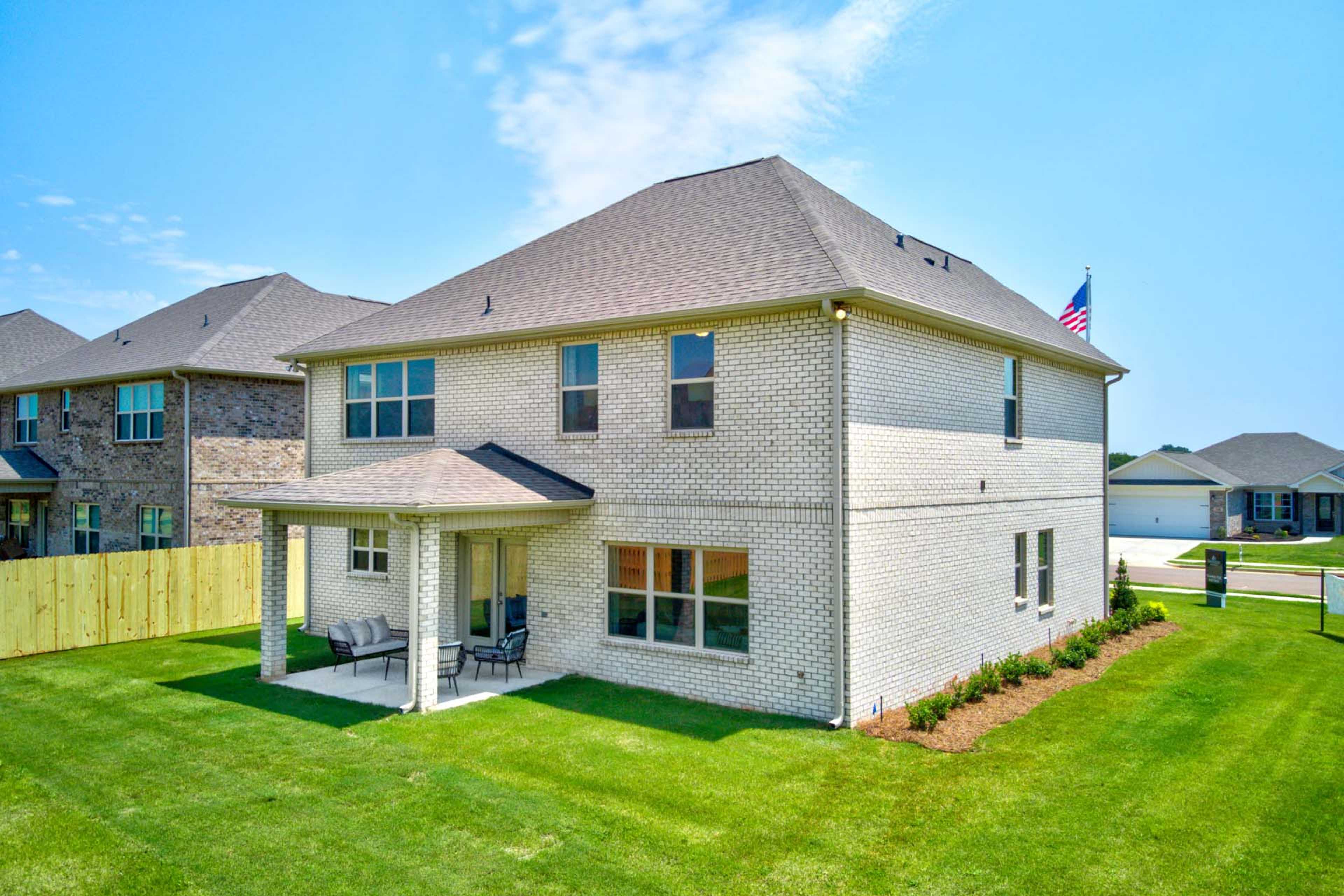 Brick home side view at Walker's Hill in Meridianville, Alabama with covered patio, lounge seating, and lush green lawn