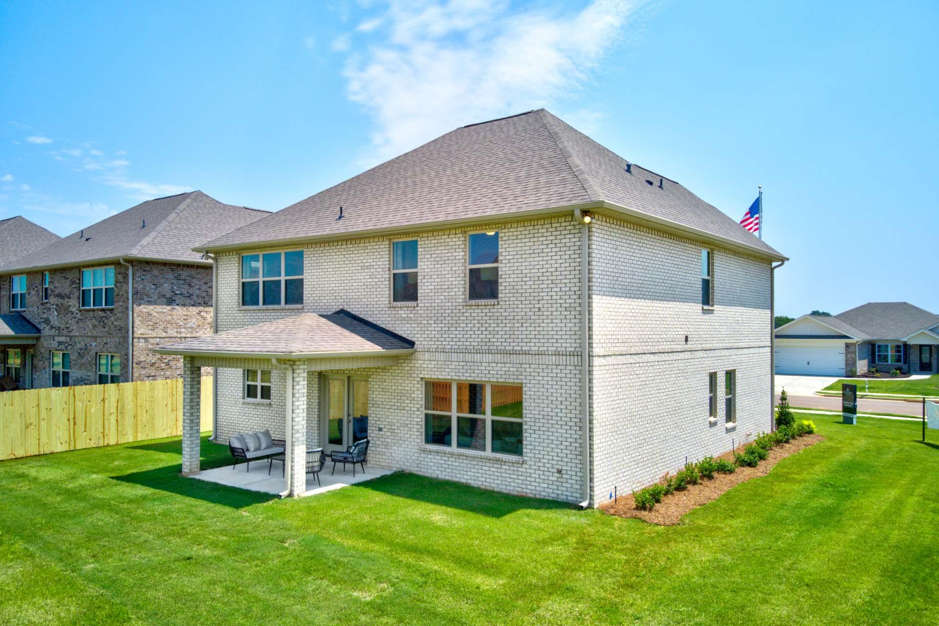 Brick home side view at Walker's Hill in Meridianville, Alabama with covered patio, lounge seating, and lush green lawn