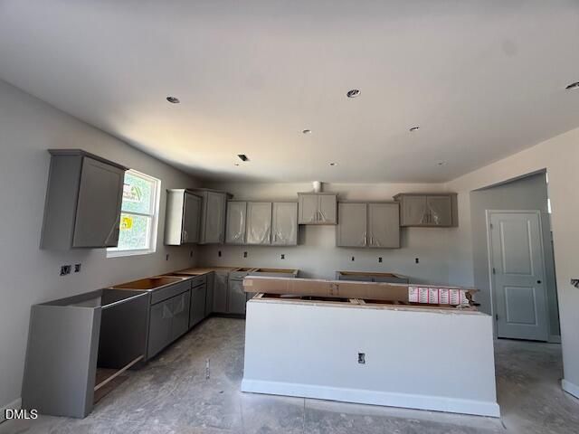 Modern gray shaker cabinets, central white island, and recessed lighting in construction kitchen of The Hickory II C, Zebulon