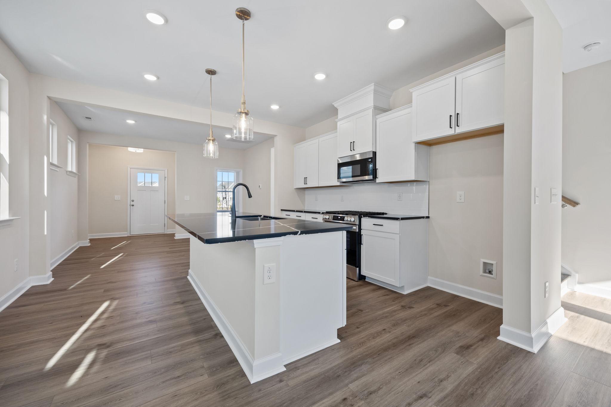 Modern kitchen at Forestville Yard in Knightdale, NC by Davidson Homes featuring white cabinets and black countertops.