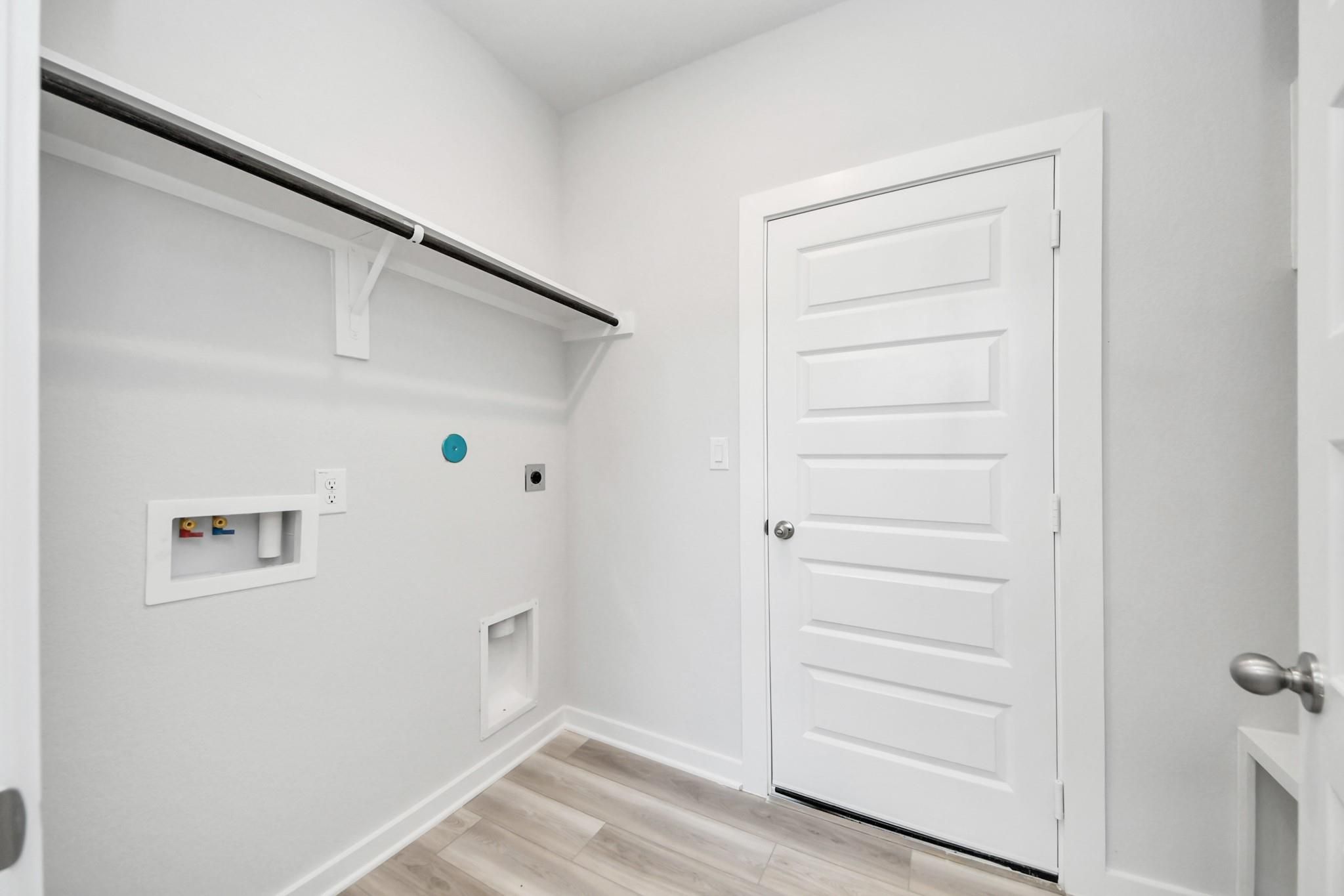 Laundry room with washer and dryer hookups and shelving in The Sabine F floor plan at Liberty Estates, Cleveland, Texas.
