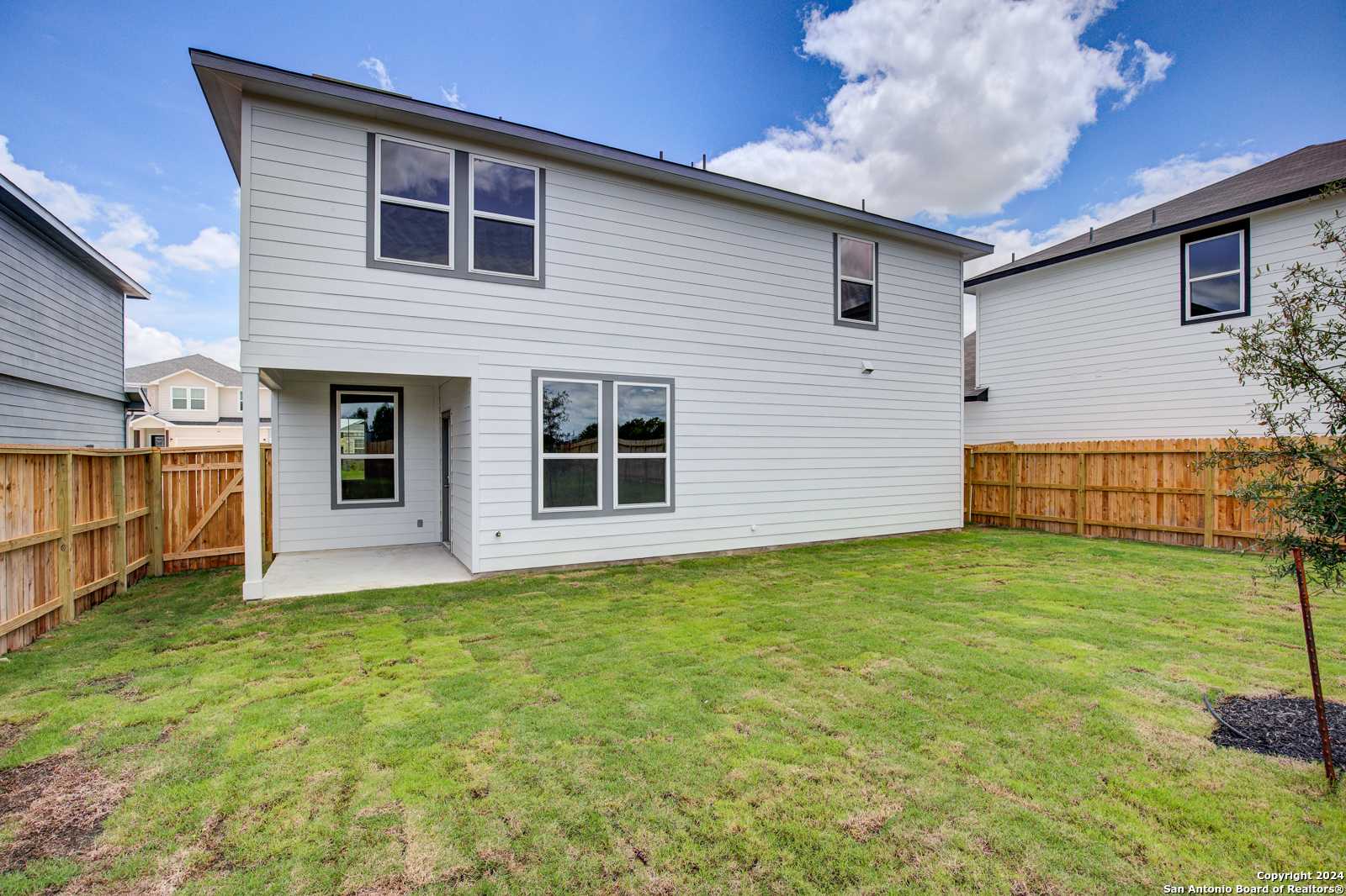 Spacious backyard with covered patio, wooden fence, and lush green lawn in Davidson Homes The Murray H, Seguin, Texas