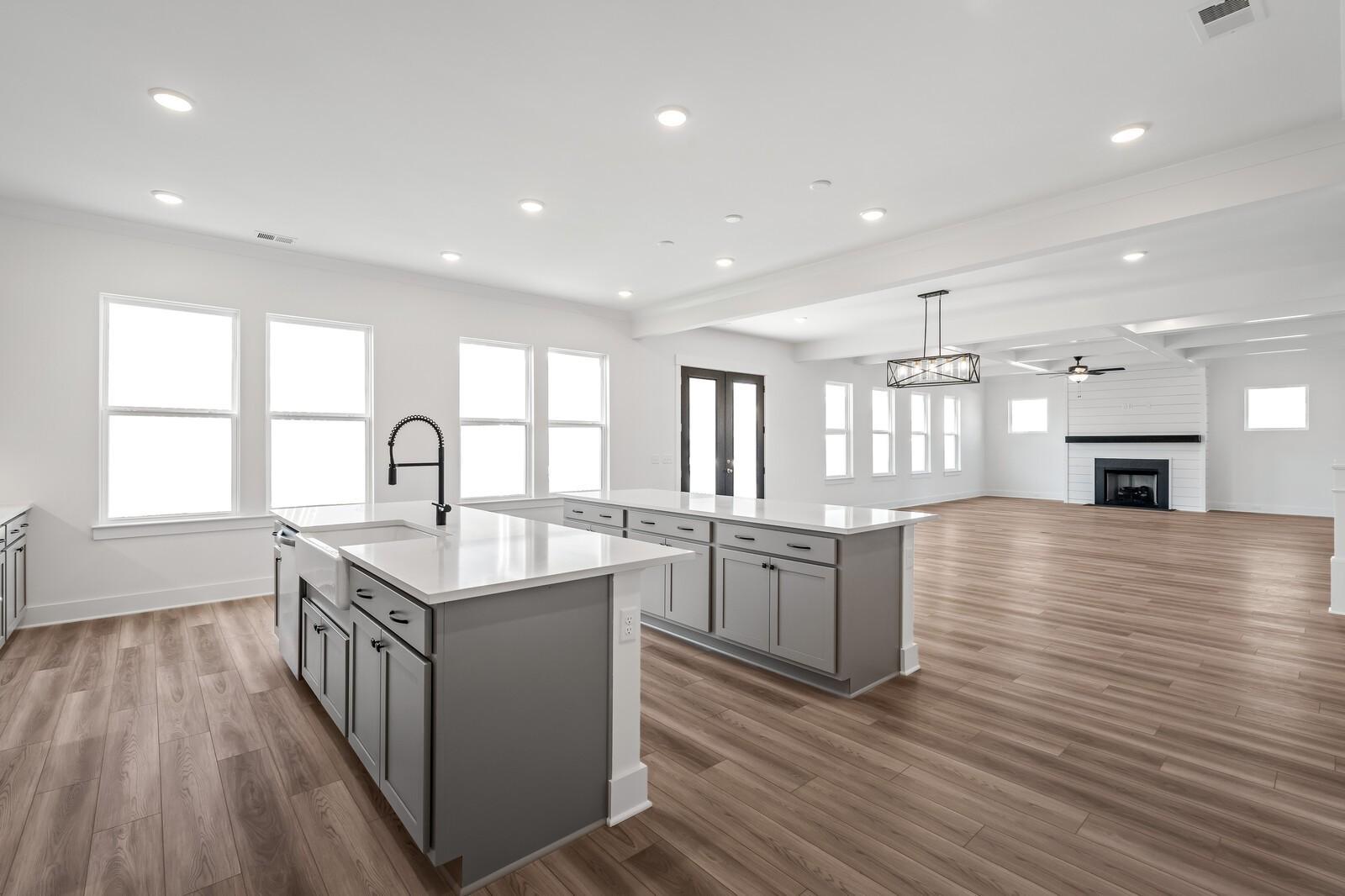 Modern open-concept kitchen with gray cabinets, white quartz island, and gas fireplace in living area, Davidson Homes The Alston A, Murfreesboro