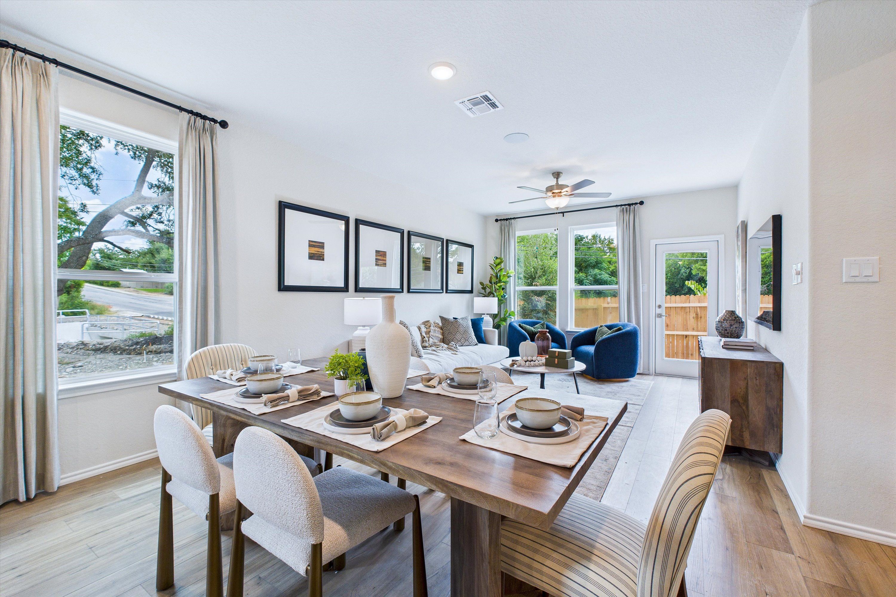 Open-concept dining and living area at Cedar Heights in San Antonio TX with wooden table, blue sofa, and large windows