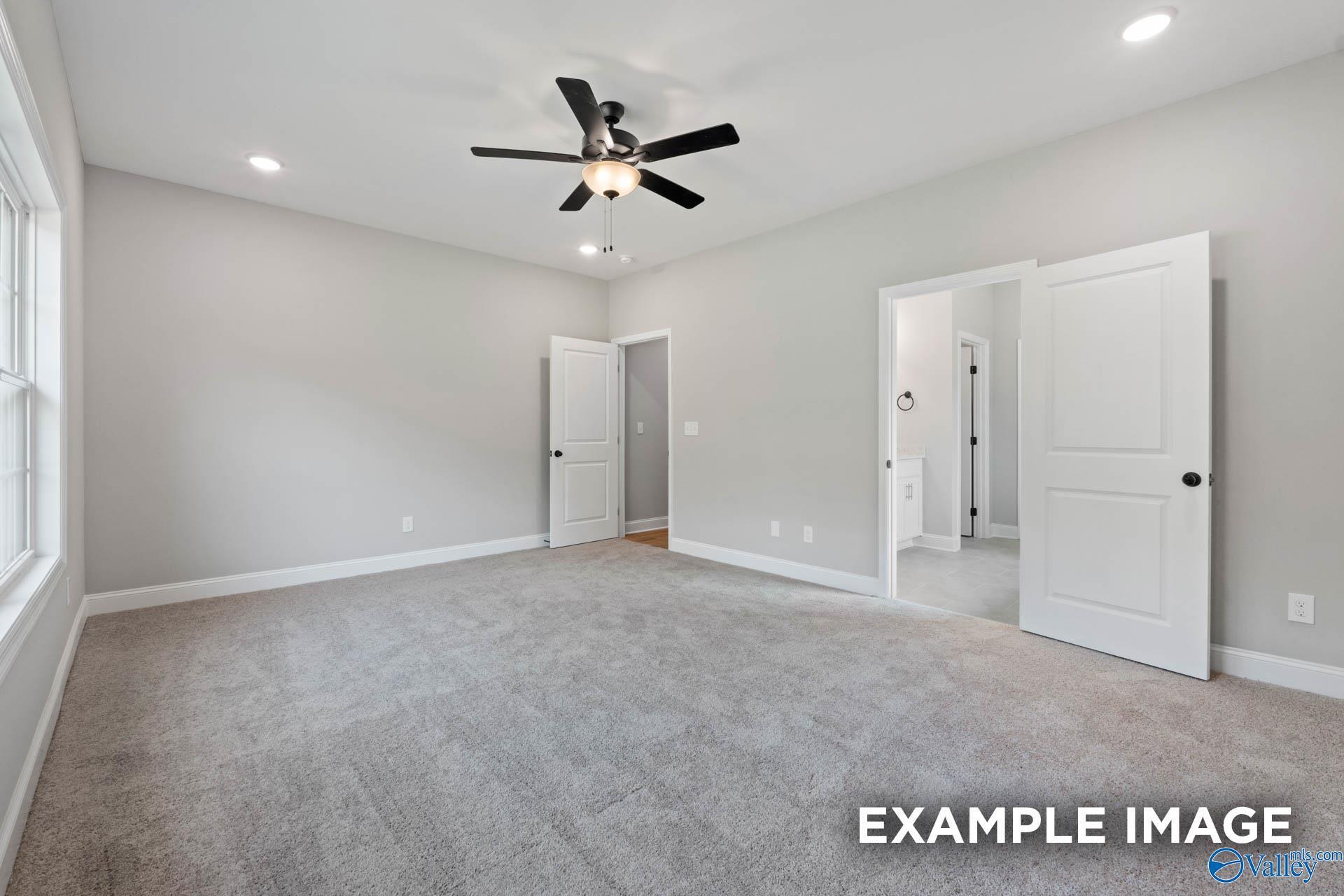 Spacious bedroom with grey carpet and ceiling fan in The Montgomery B floor plan by Davidson Homes in Decatur, Alabama.