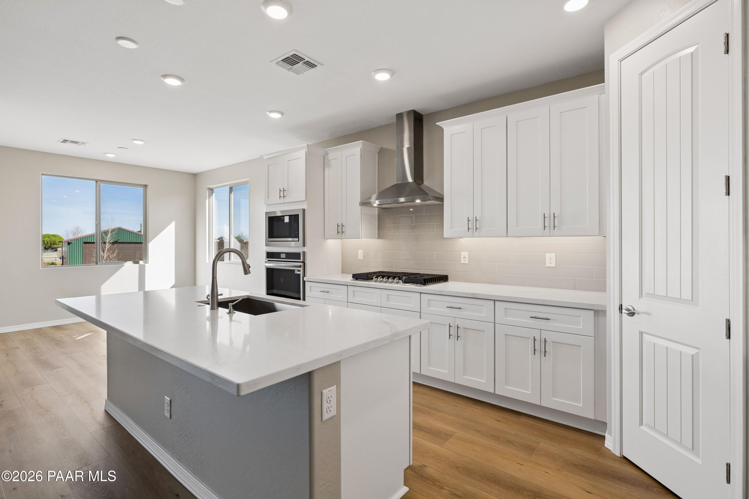 Modern white kitchen with large island, stainless steel appliances, and sunny windows in Davidson Homes The Harmony A, Prescott Valley, AZ