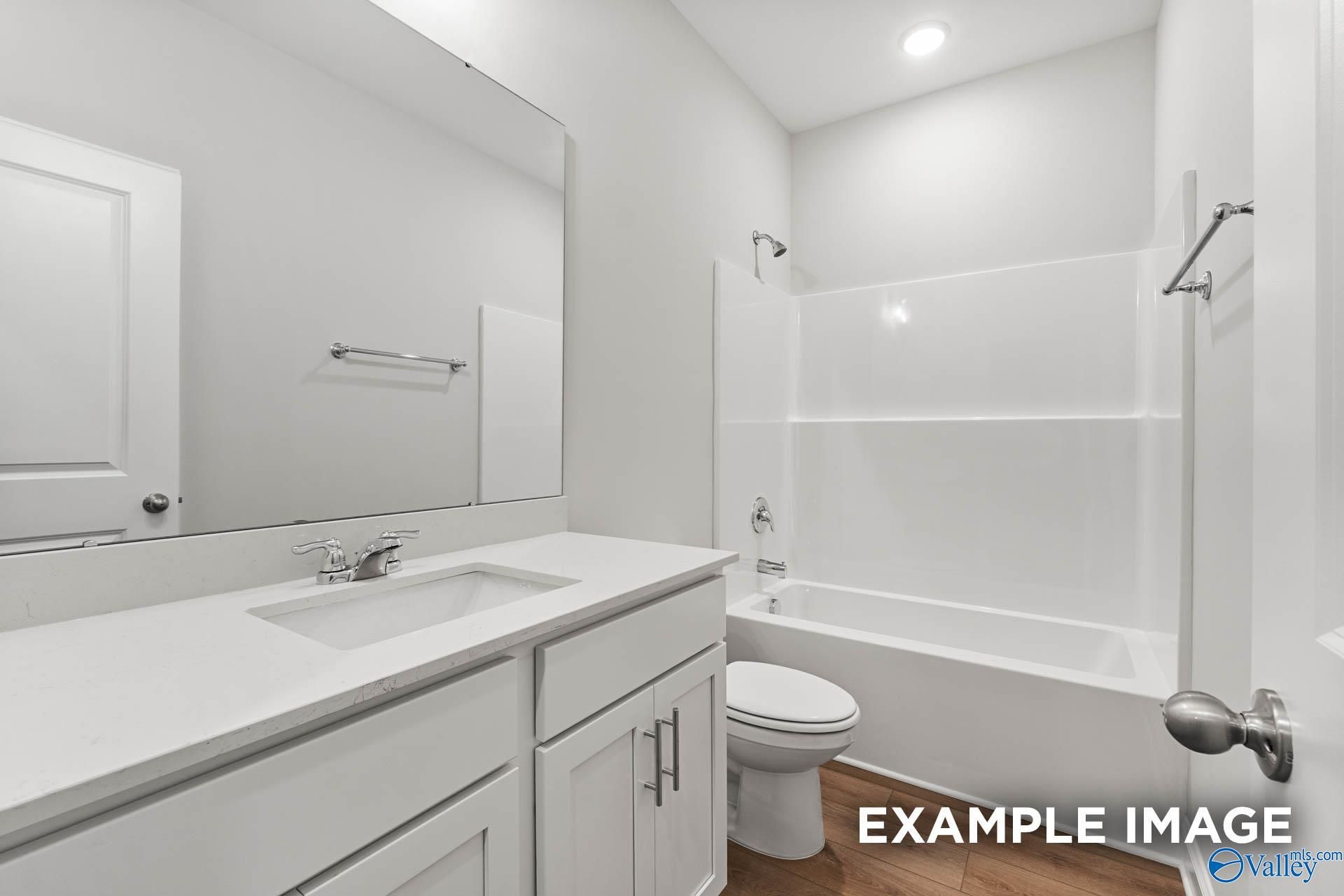 Bright white secondary bathroom with single vanity, bathtub-shower combo, and toilet in Davidson Homes The Daphne, Meridianville, AL