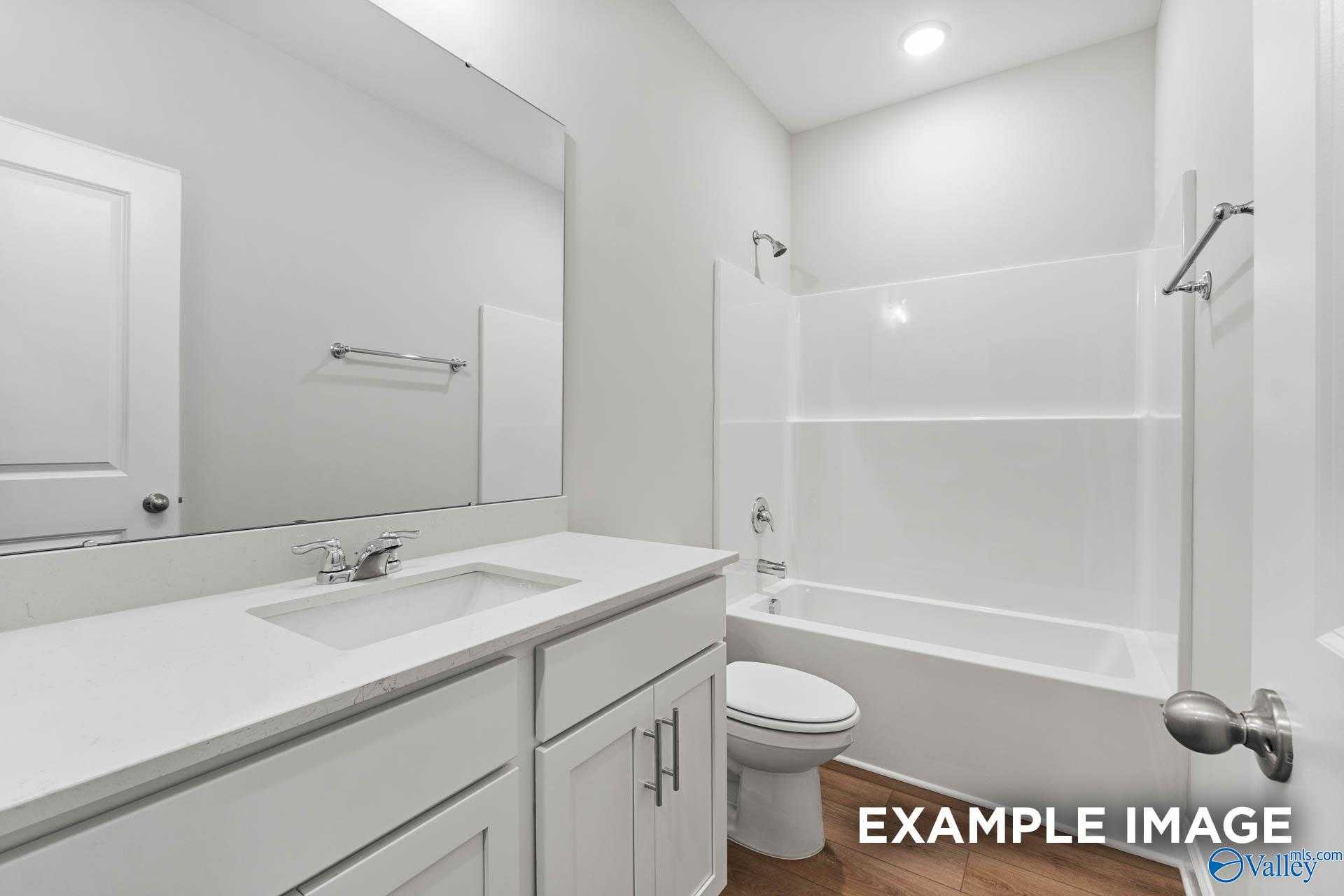 Bright white secondary bathroom with single vanity, bathtub-shower combo, and toilet in Davidson Homes The Daphne, Meridianville, AL