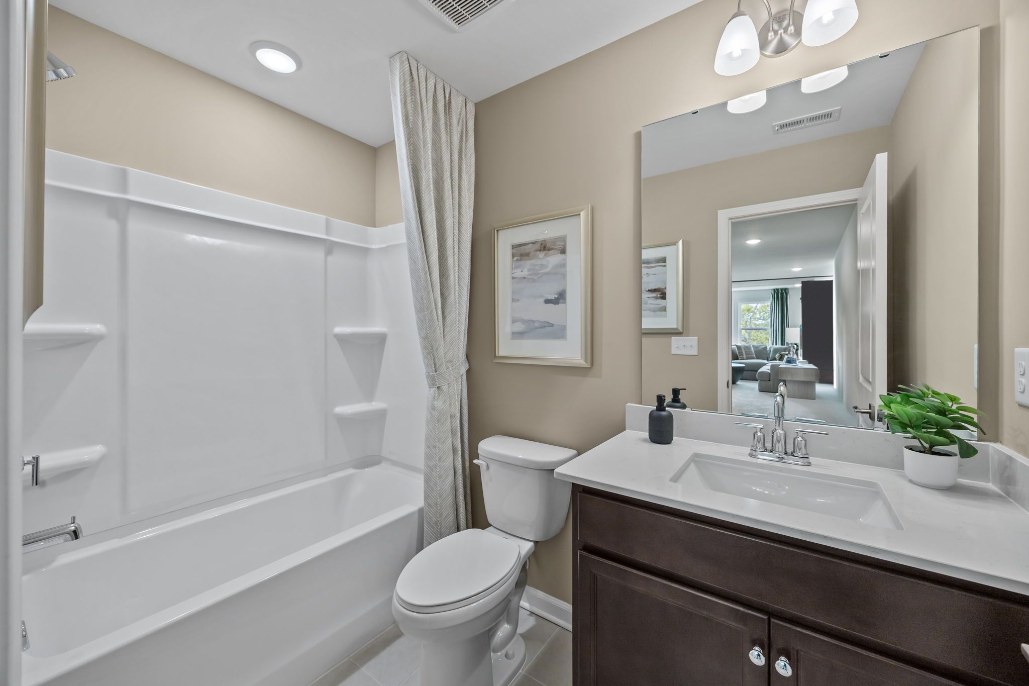Modern bathroom in Springvale South, Fuquay-Varina with dark wood vanity, white quartz countertop, and tub-shower combo.