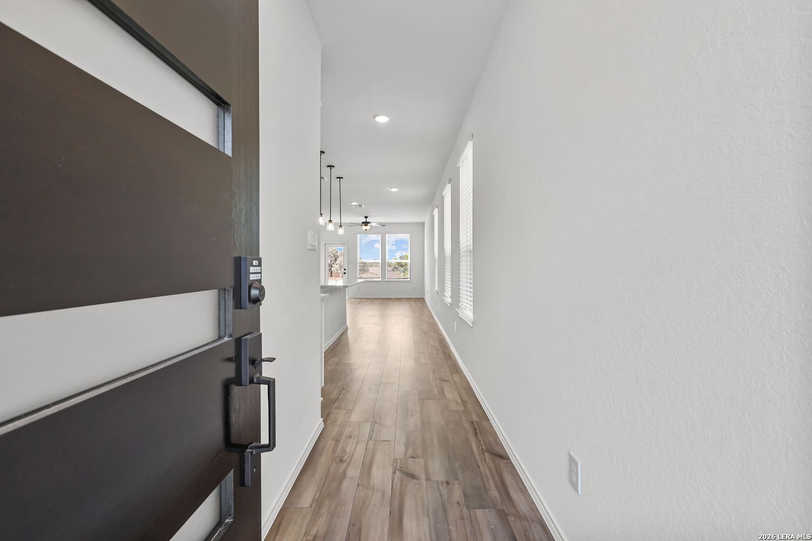 Bright entryway with wood-look flooring leading into The Gillian C floor plan home in Meadows at Oak Creek, San Antonio.
