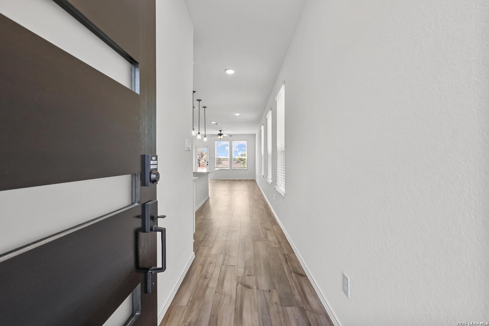Bright entryway with wood-look flooring leading into The Gillian C floor plan home in Meadows at Oak Creek, San Antonio.