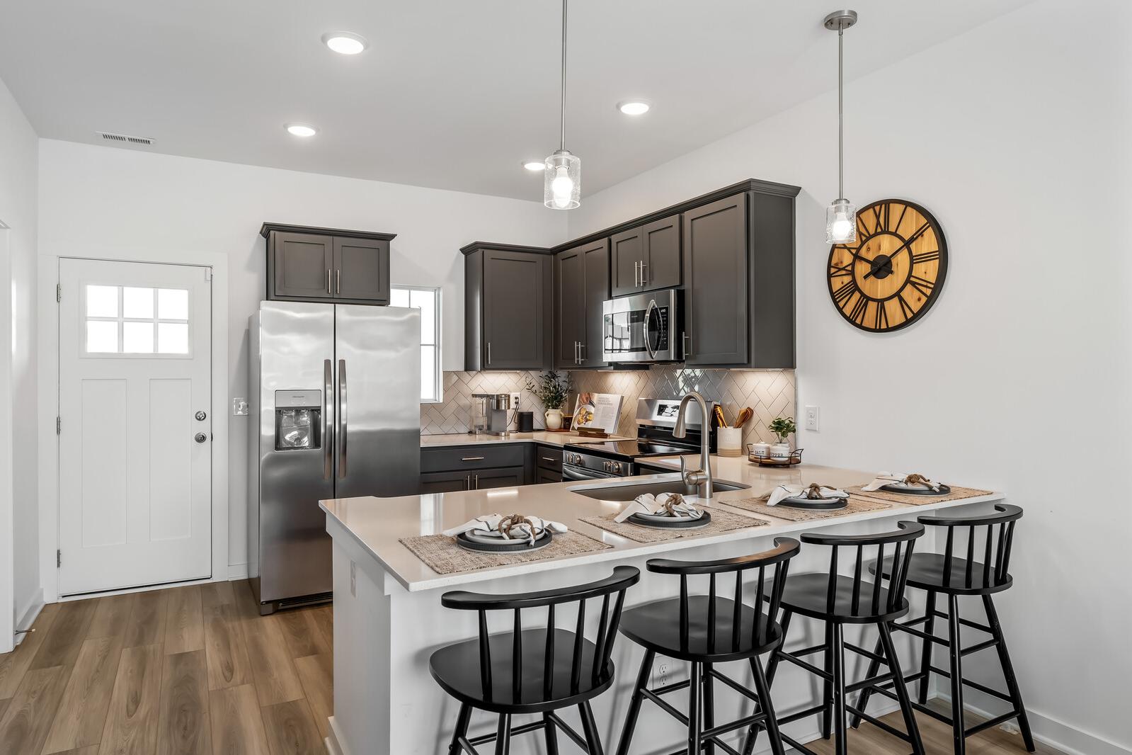 Modern gray kitchen at The Towns at Red River in Gallatin TN with stainless appliances, breakfast island, and hardwood floors