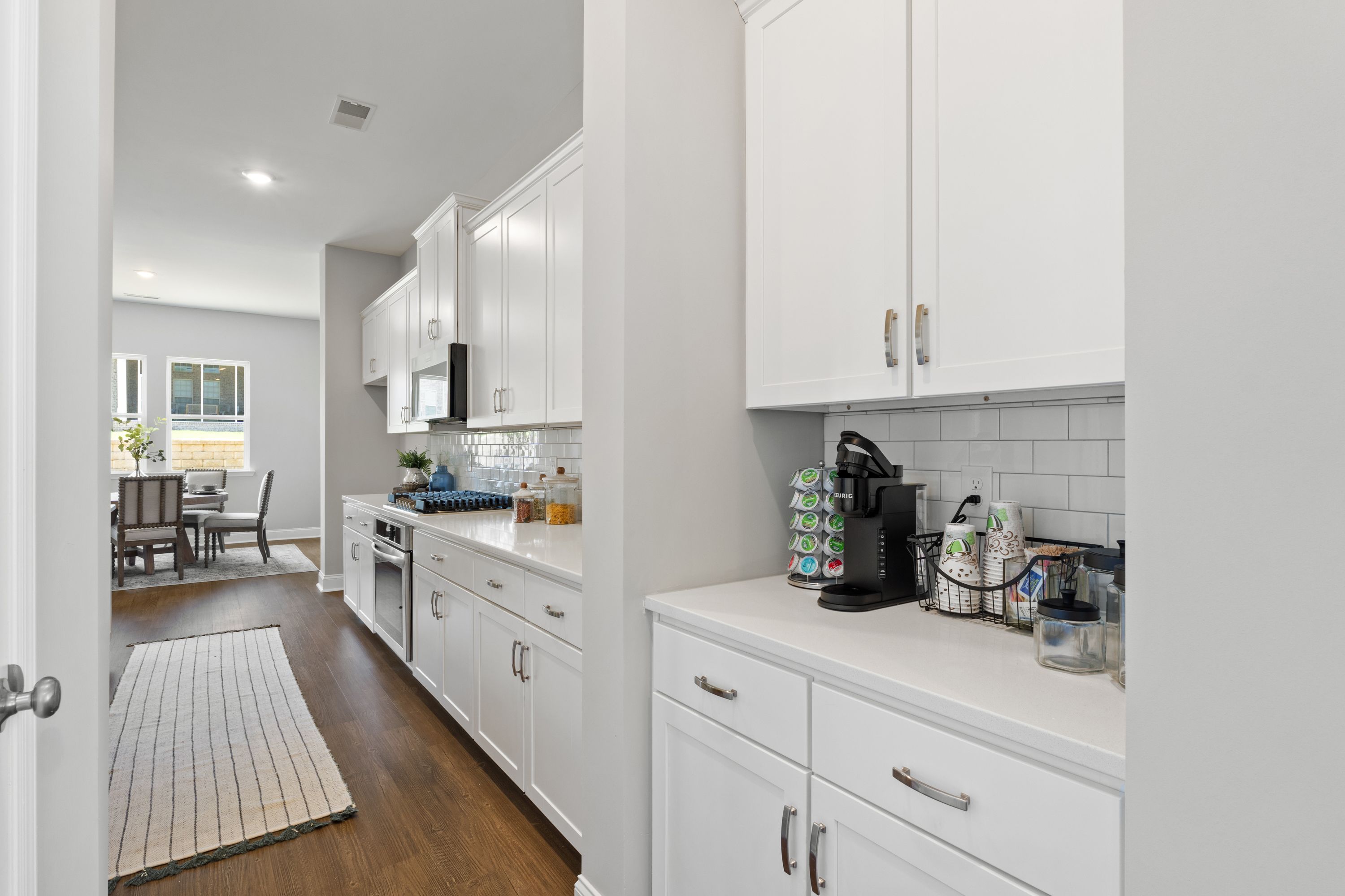 Spacious kitchen in The Haven D with white shaker cabinets, subway tile backsplash, and Keurig coffee station