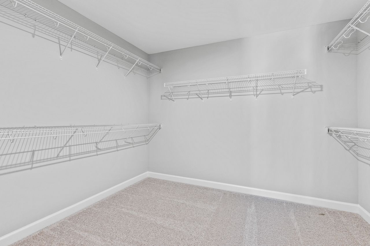 Spacious walk-in closet in The Hemlock master suite featuring wire shelving and neutral carpeting.