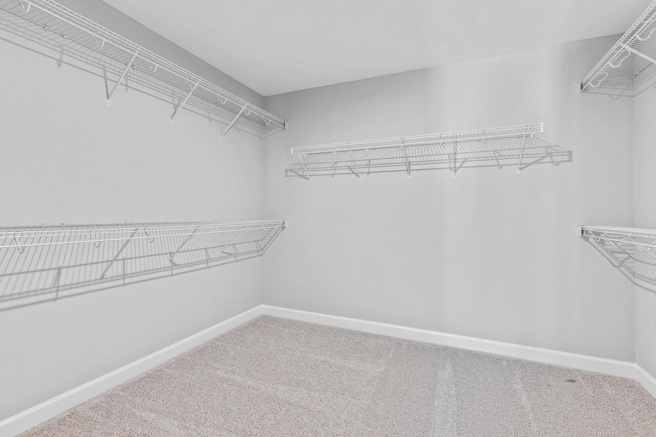 Spacious walk-in closet in The Hemlock master suite featuring wire shelving and neutral carpeting.
