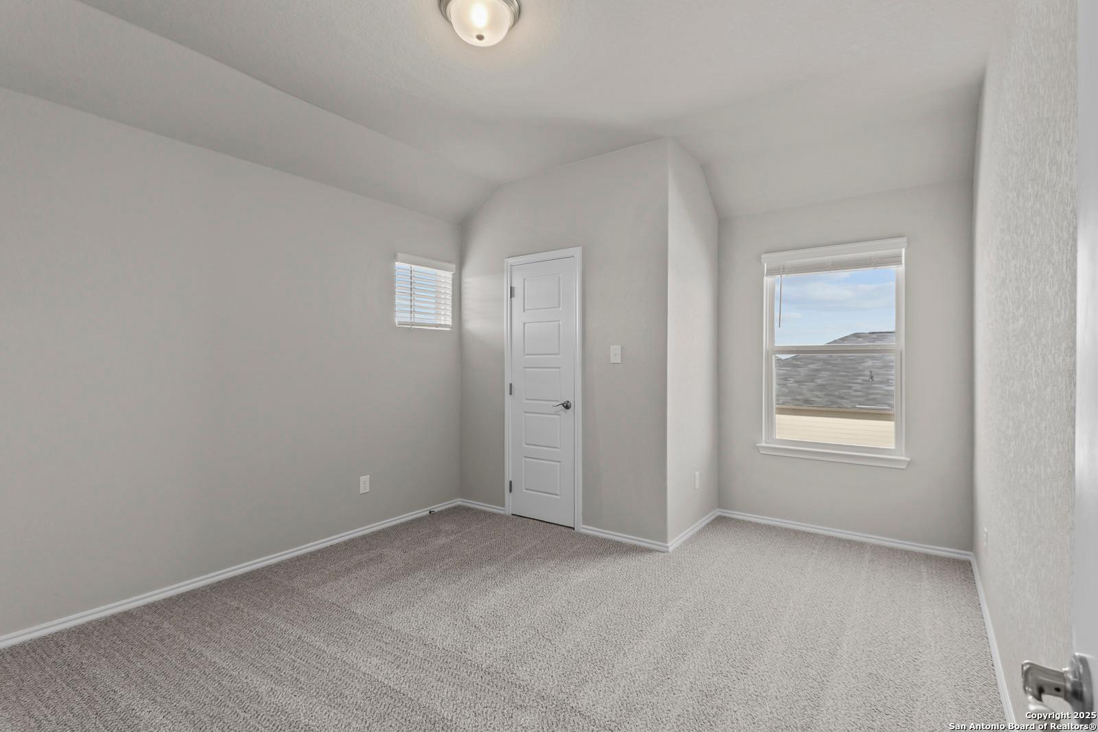 Cozy secondary bedroom with light gray walls, beige carpet, and window view in Davidson Homes The Collin B, Seguin TX