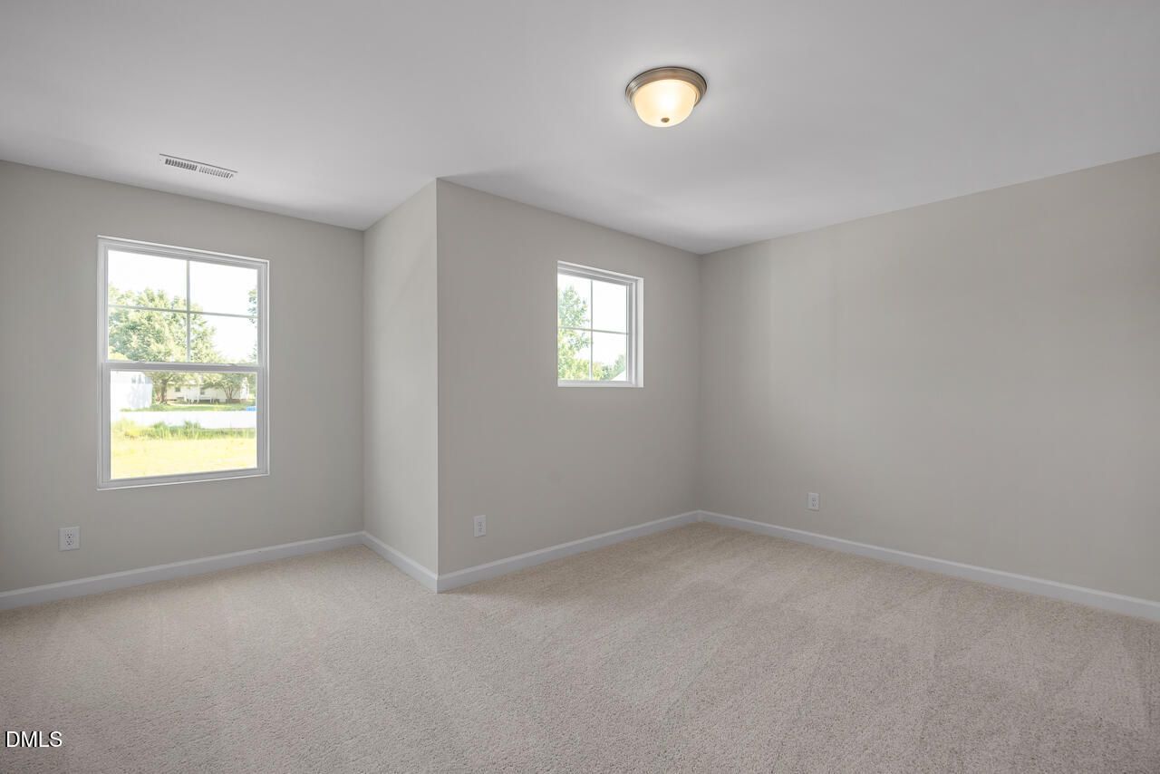 Bright secondary bedroom with neutral walls, double windows, and carpet flooring in Davidson Homes The Preston A, Lillington, NC