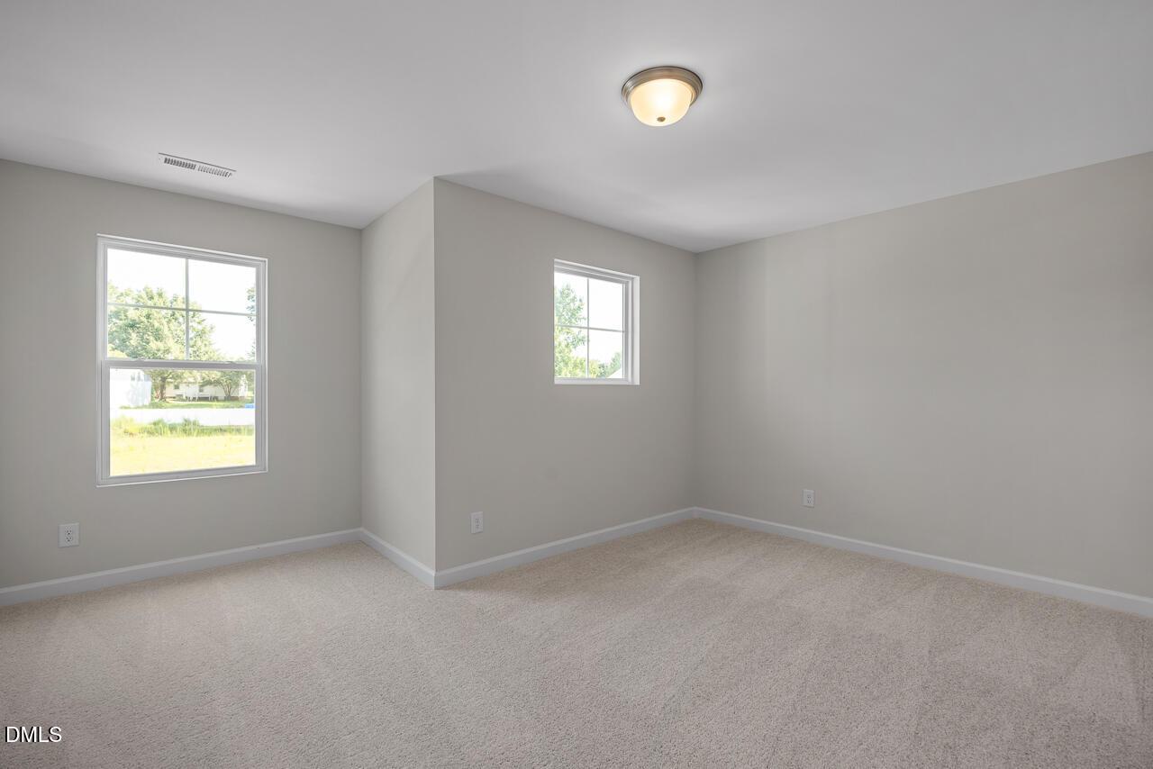 Bright secondary bedroom with neutral walls, double windows, and carpet flooring in Davidson Homes The Preston A, Lillington, NC