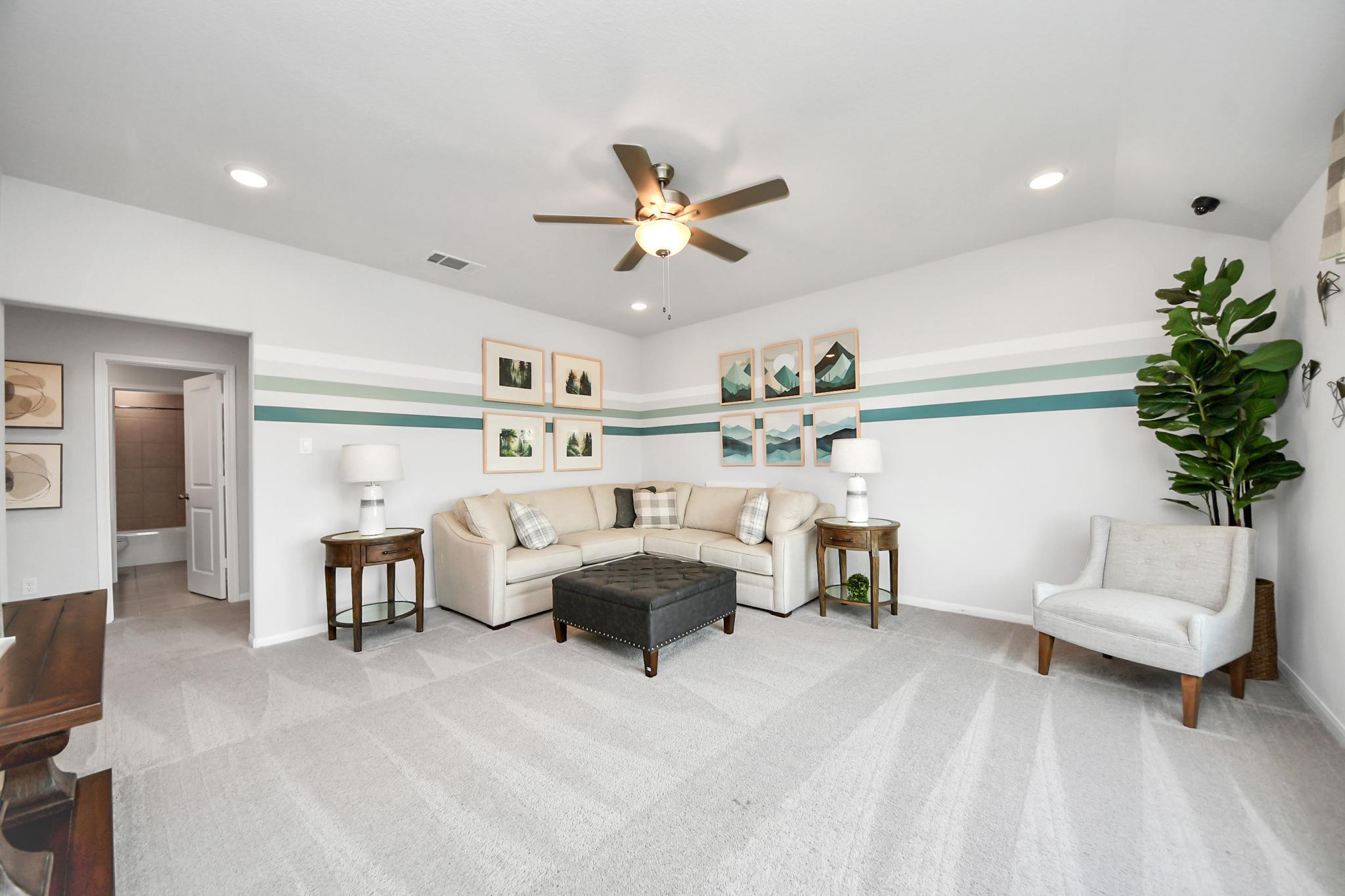 Cozy living room in a Sunterra home by Davidson Homes in Katy, Texas, featuring a sectional sofa and modern wall decor.