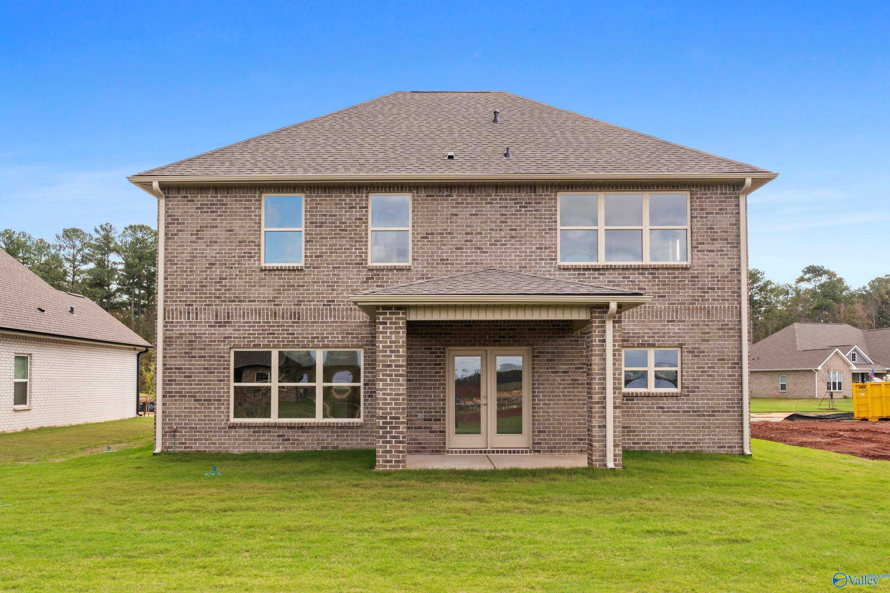 Two-story brick home with covered front porch, double doors, and gabled roof on green lawn in Creekside, Harvest, AL - Davidson Homes Chelsea C