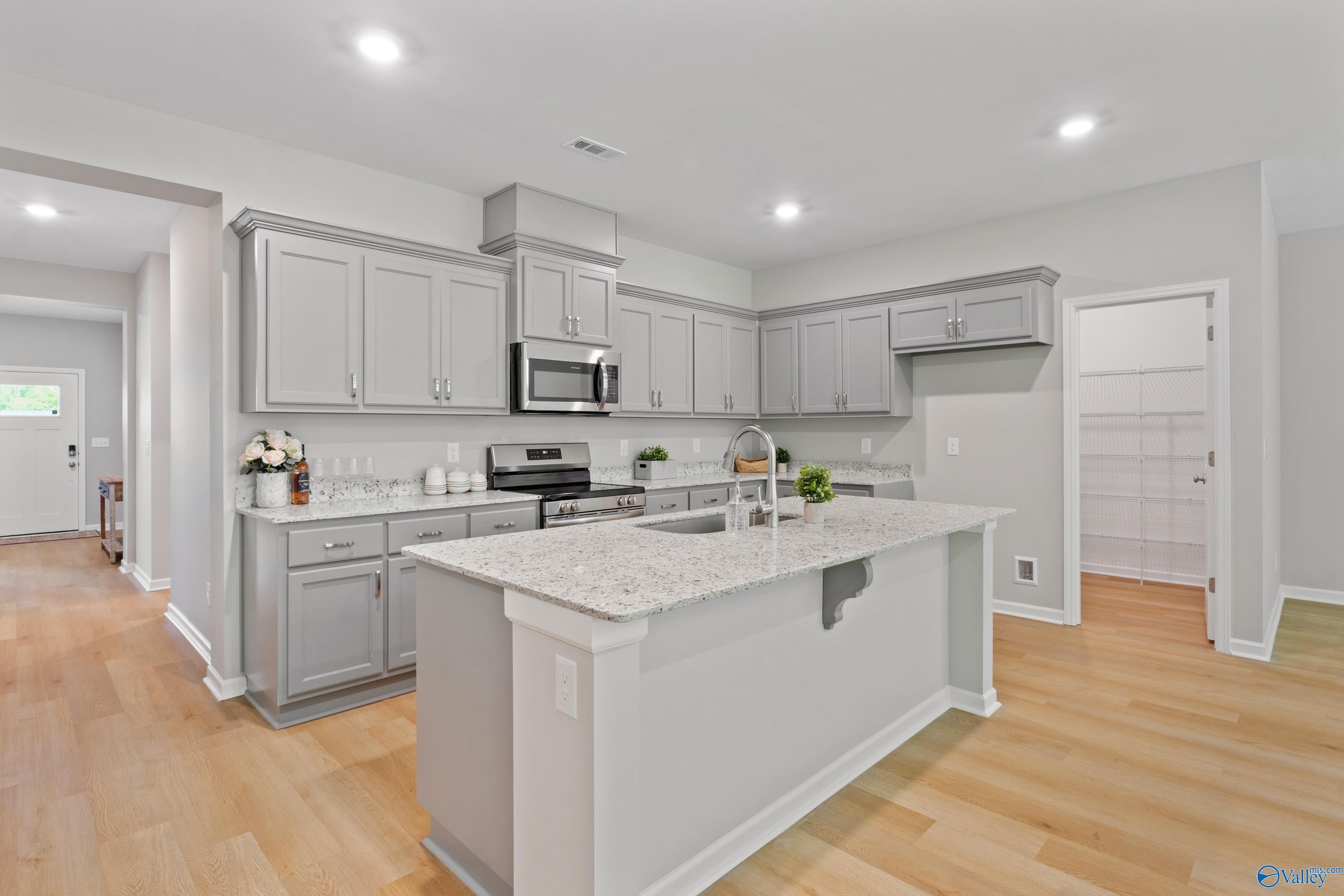 Modern kitchen with gray shaker cabinets, white quartz island sink, stainless appliances in Davidson Homes The Luna, Hazel Green, AL