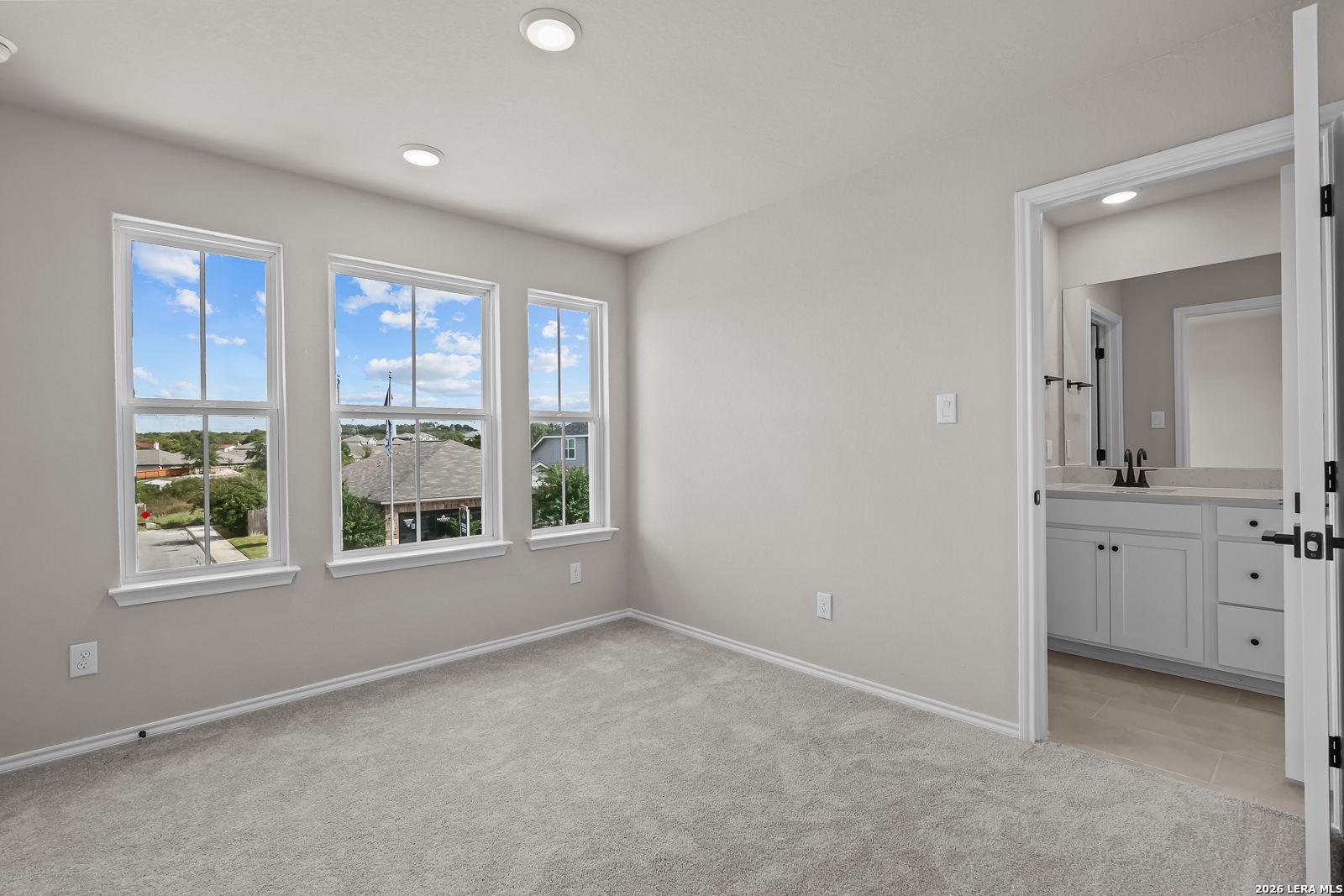 Bright carpeted bedroom with multiple windows and attached bath in Davidson Homes The Sequoia C, Royal Crest, San Antonio, Texas