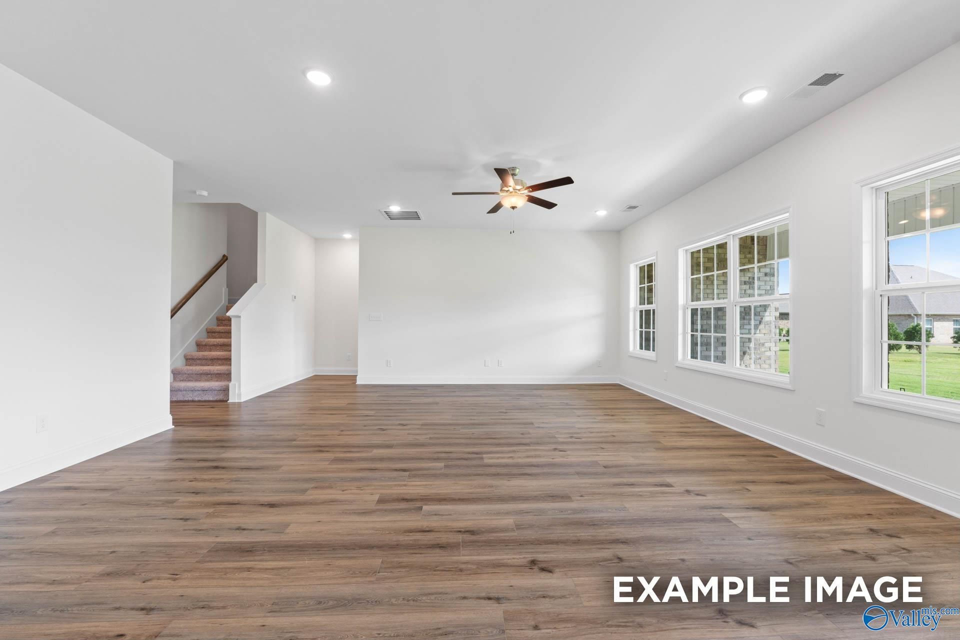 Spacious, sunlit open-concept living area with wood-style flooring in The Rockford B floor plan, Kendall Downs, Toney, AL.