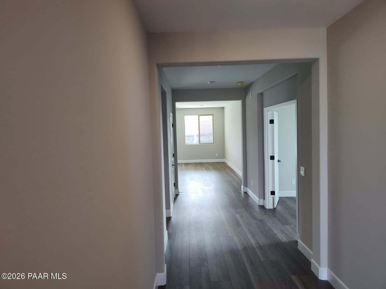 Wide hallway with dark hardwood floors, gray walls, and adjacent doors in Davidson Homes The Harmony C, Prescott Valley, AZ