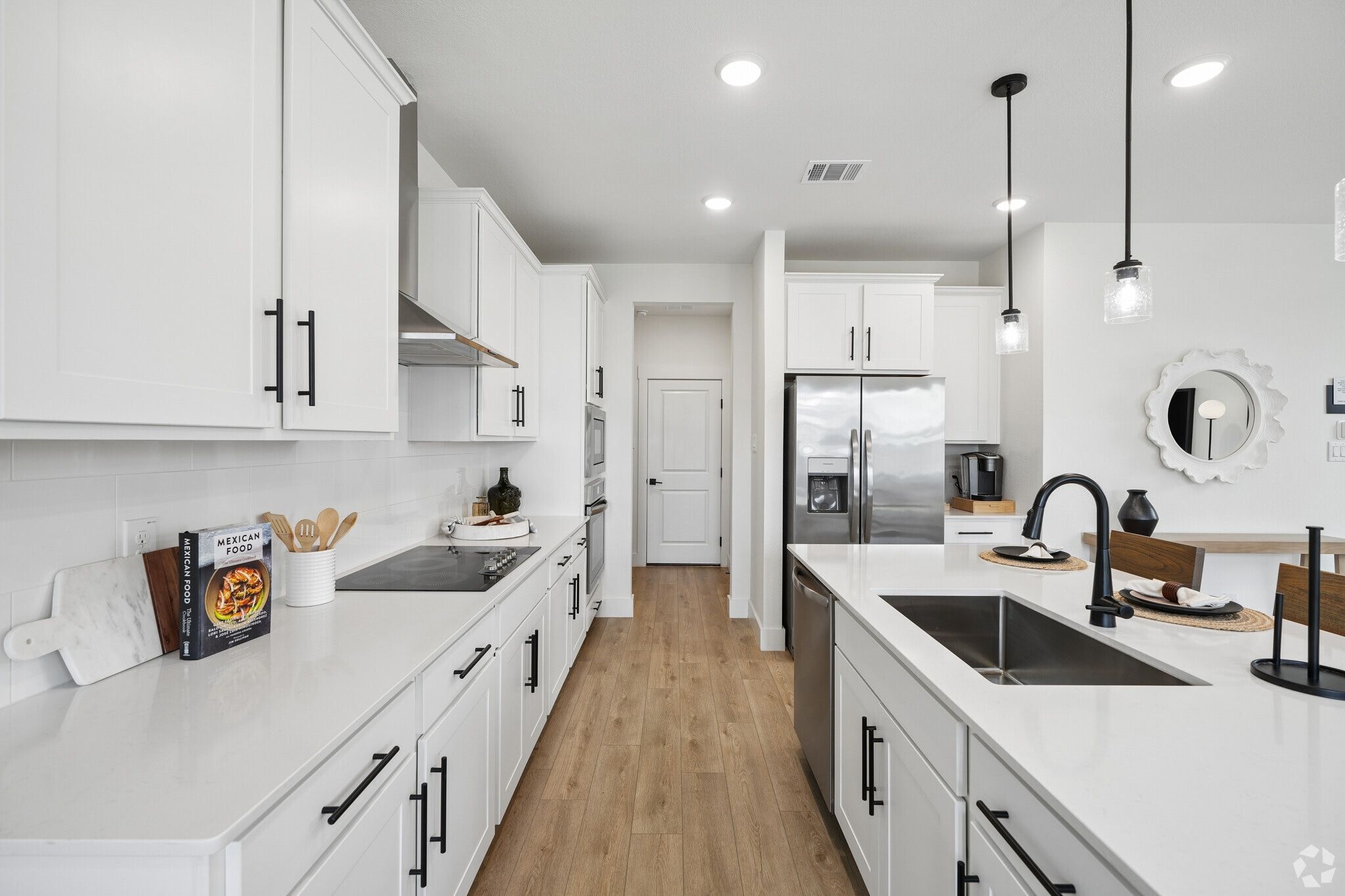 Modern kitchen with white cabinets, stainless appliances and pendant lights