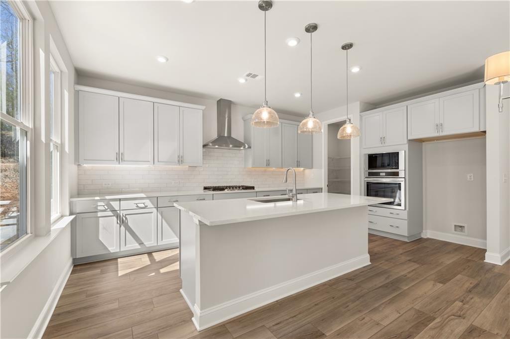 Bright modern kitchen with white shaker cabinets, quartz island, stainless appliances, subway tile backsplash in Danbury C, Buford GA