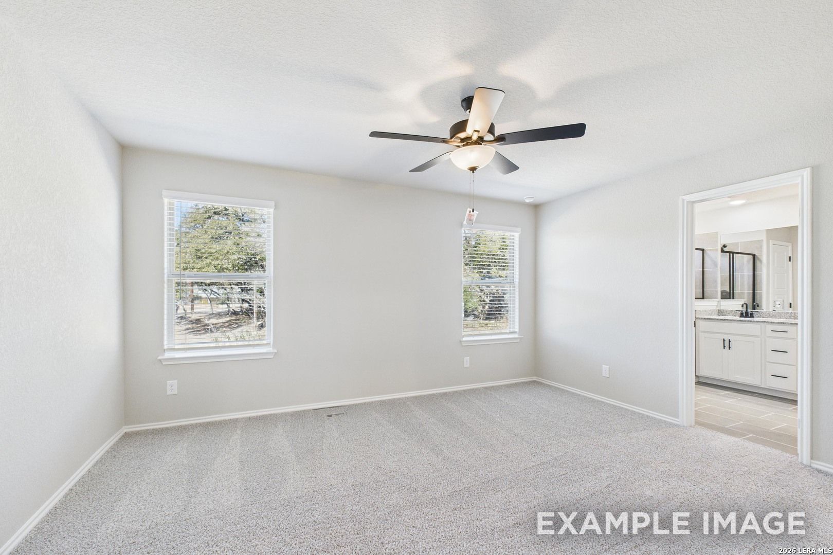 Bright bedroom with neutral carpet, ceiling fan, and en-suite bathroom in The Charlotte B floor plan, Cedar Heights.
