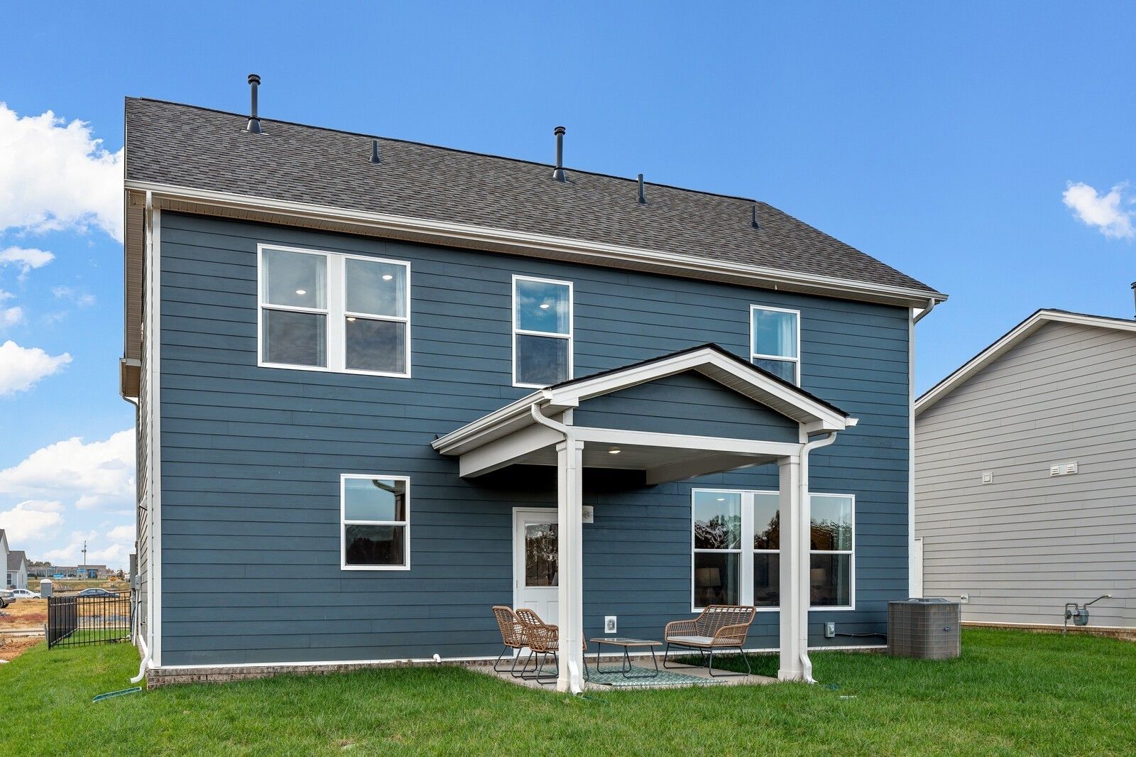 Navy blue two-story home with covered front porch, wicker chairs, large windows in Sage Farms, White House, Tennessee - Davidson Homes Gordon C