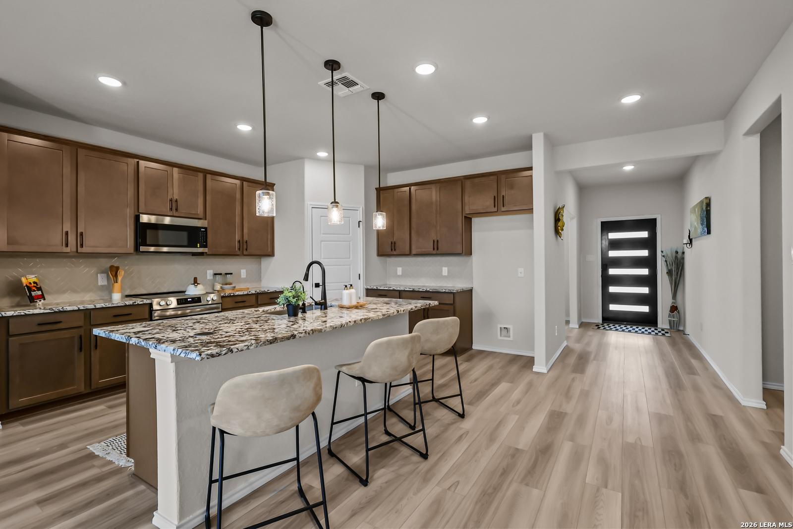 Modern kitchen with granite island and pendant lighting in The Douglas C floor plan at Hannah Heights, Seguin, Texas.