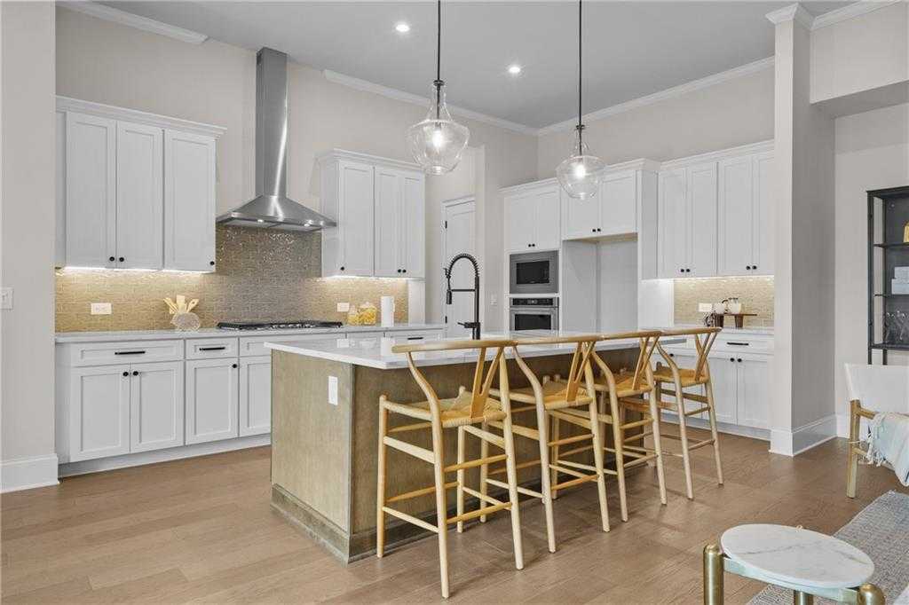 Modern white kitchen with large island, stainless steel appliances, and pendant lights in Davidson Homes Seaside B, Woodstock, GA