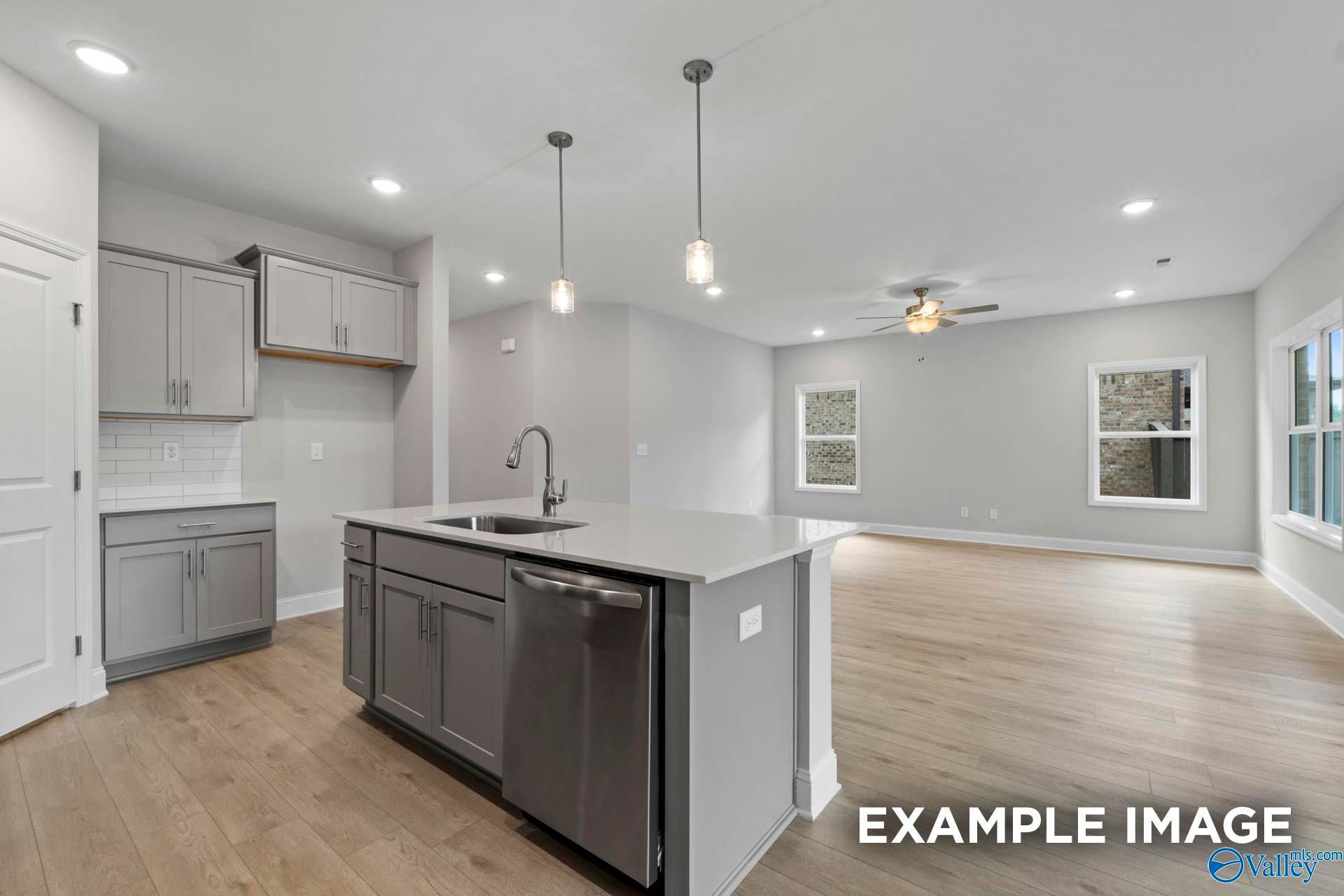 Open-concept kitchen with gray cabinets and island in The Franklin C floor plan at Noble Ridge, Cullman, Alabama.