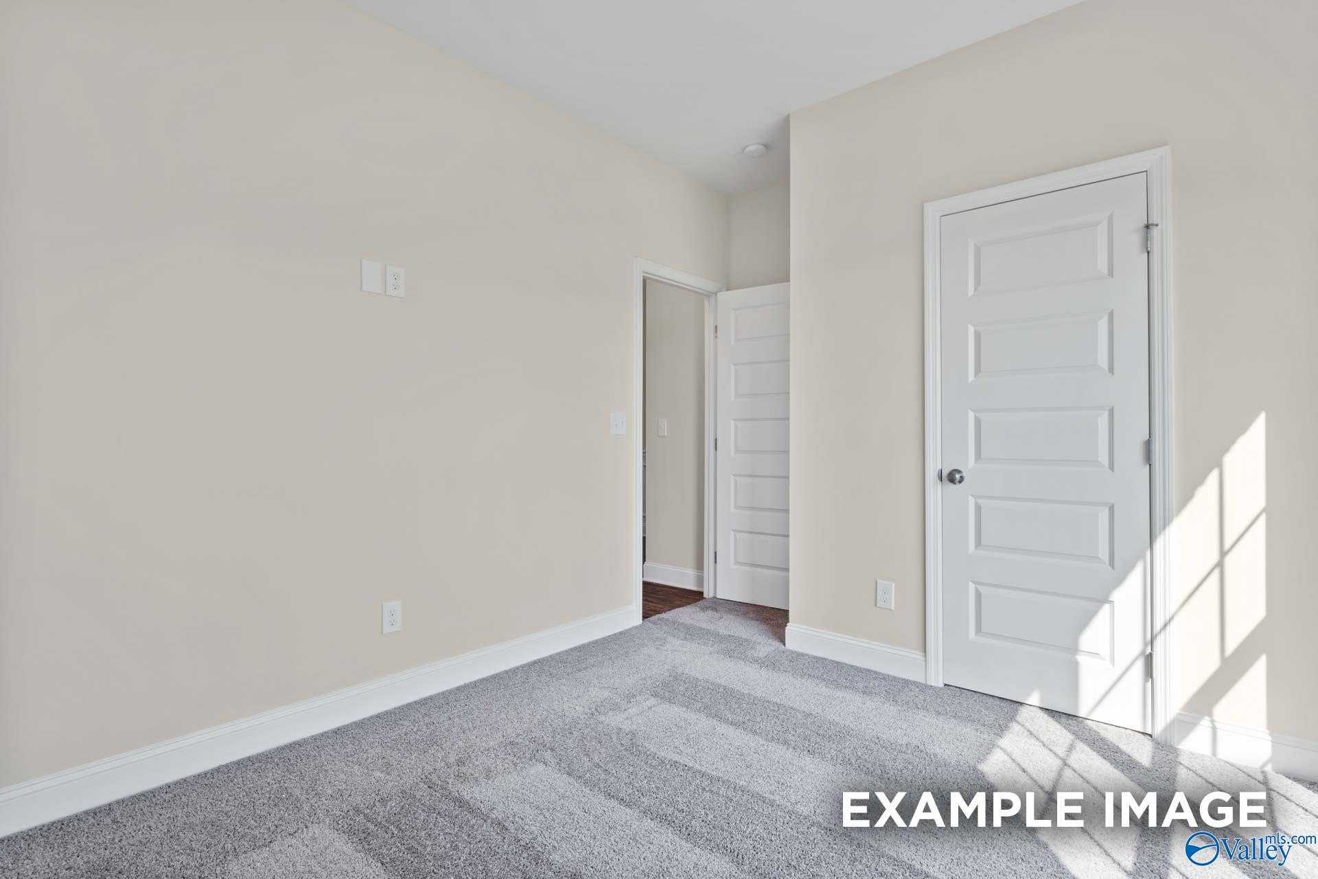 Bright secondary bedroom with beige walls, gray carpet, white doors to bath and closet in The Asheville plan, Arab, AL