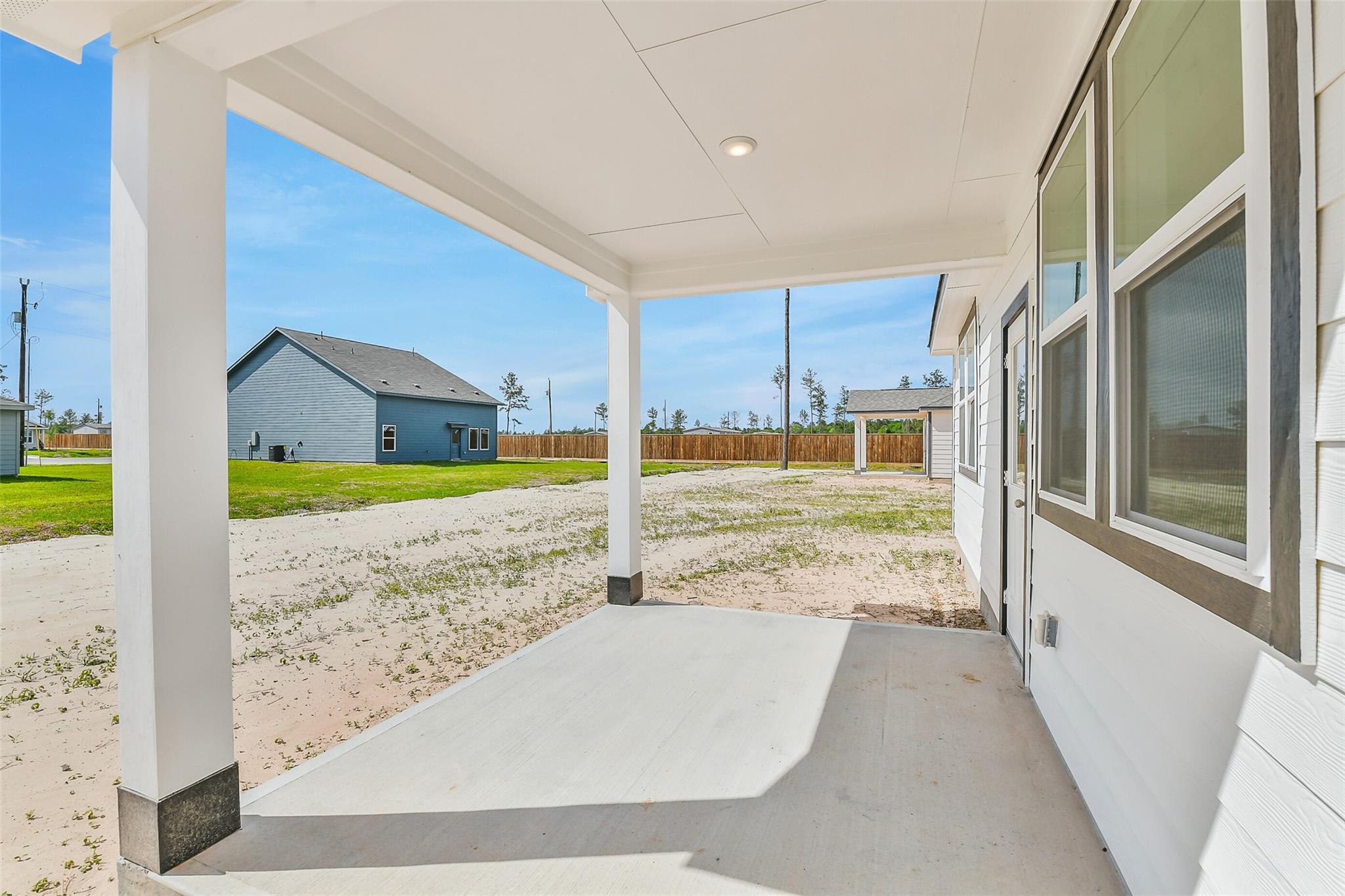 Inviting covered front porch with white columns and concrete flooring on Davidson Homes The Frio G in Conroe, Texas
