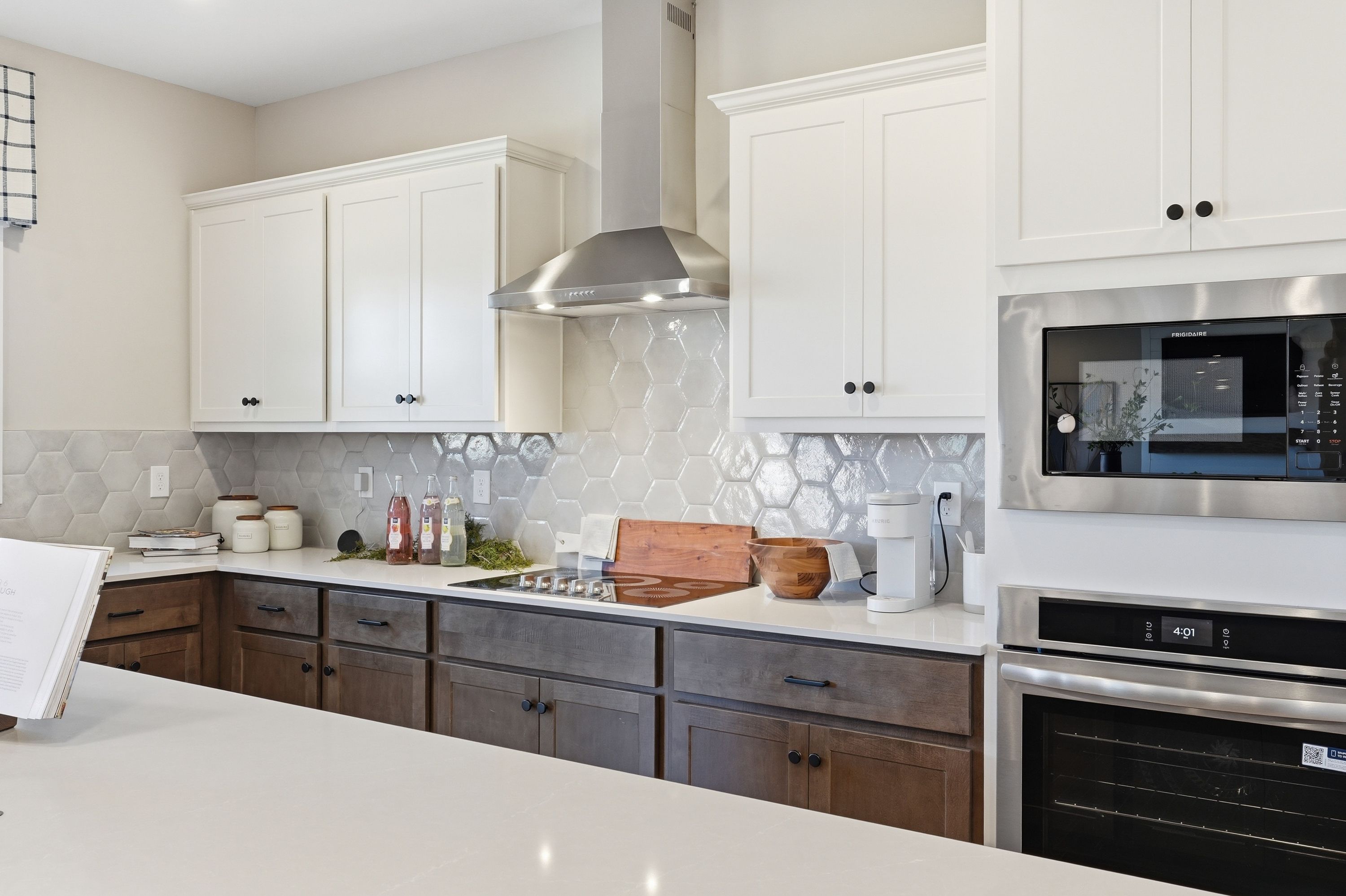 Modern kitchen in Berry Cove, New Market Alabama with white shaker cabinets, dark wood lowers, stainless appliances and subway tile backsplash