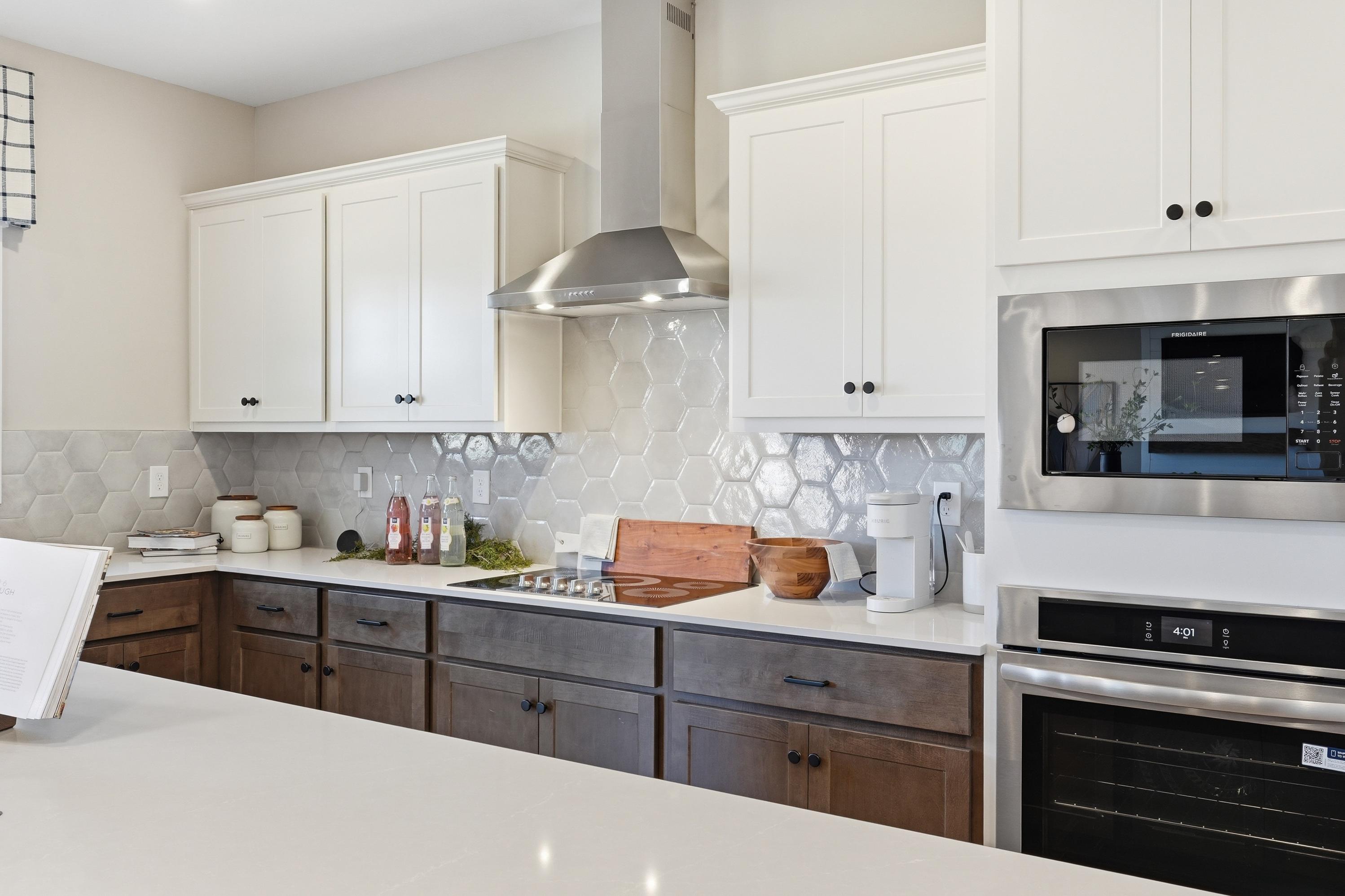 Modern kitchen in Berry Cove, New Market Alabama with white shaker cabinets, dark wood lowers, stainless appliances and subway tile backsplash