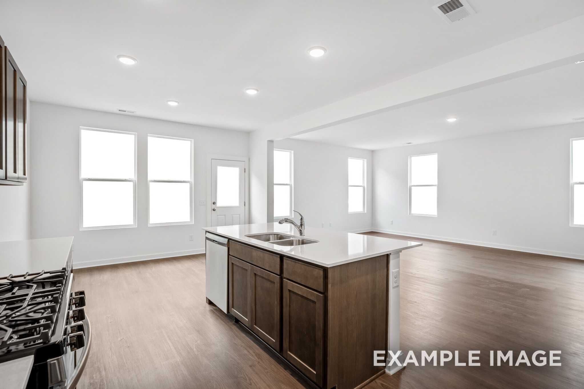 Spacious Grayson C kitchen with large center island, gas range, white cabinets, and open hardwood floor plan