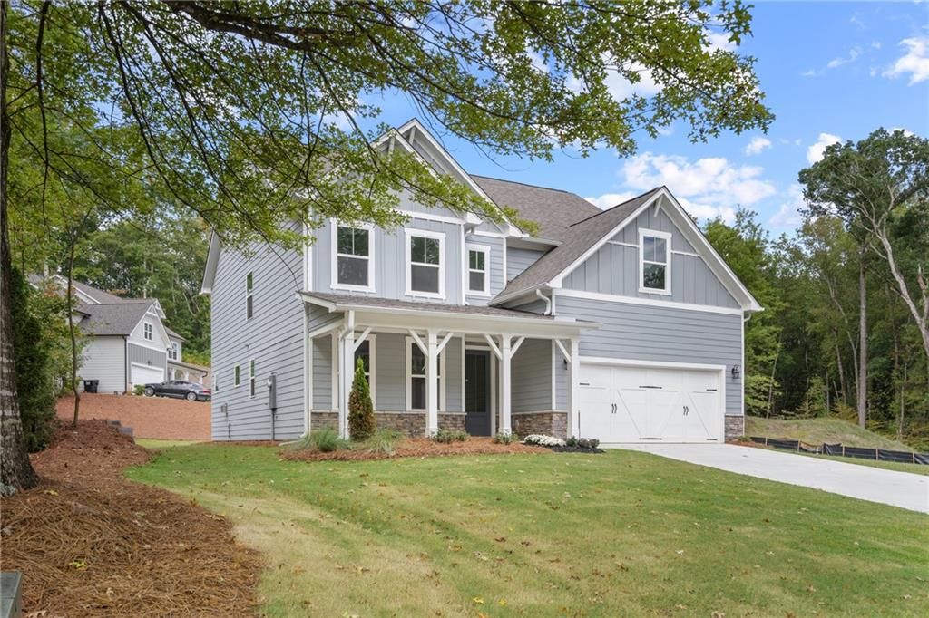 Two-story gray home with covered front porch, 4-car garage, and lush lawn in Riverwood, Davidson Homes The Willow B, Dallas, Georgia